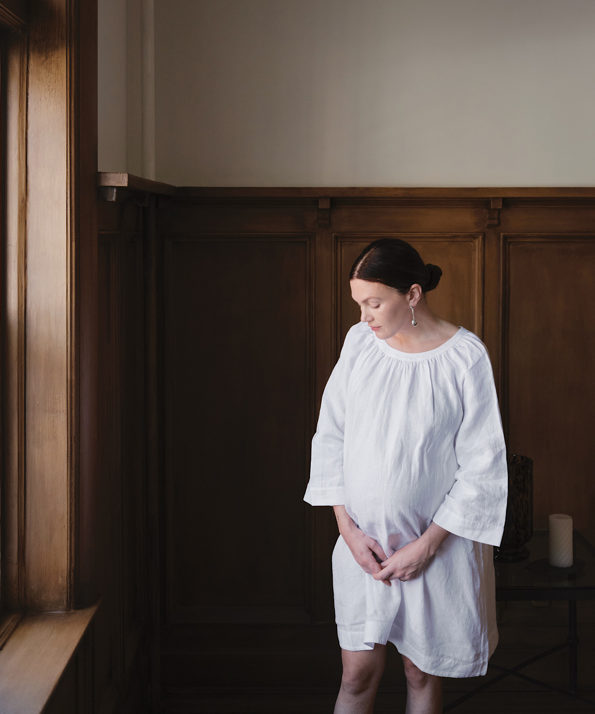 madelynn hudson in a white linen dress with camel ballet flats standing in her dining room