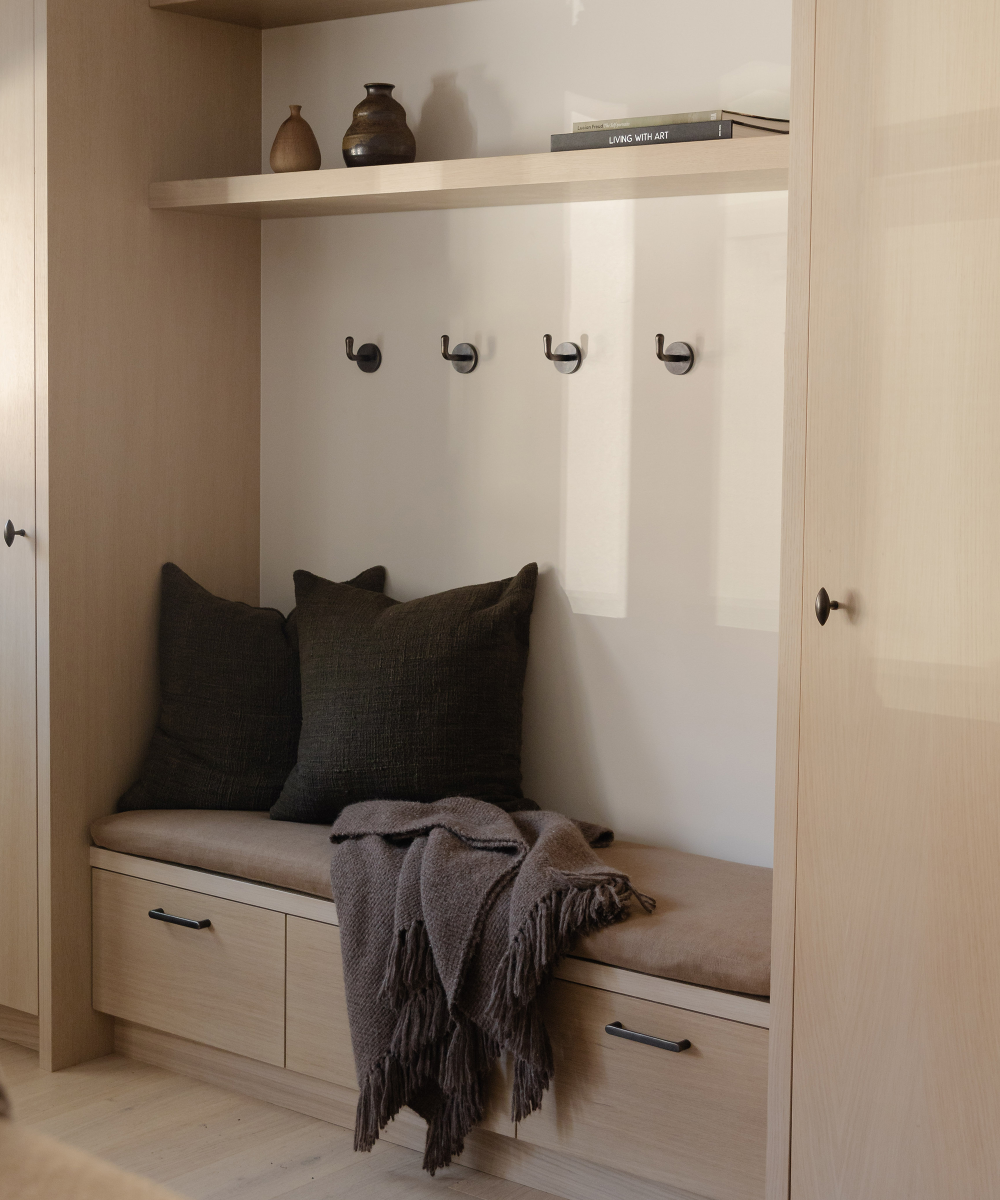 a built-in nook with a bench and two cocoa accent pillows and a throw with drawers