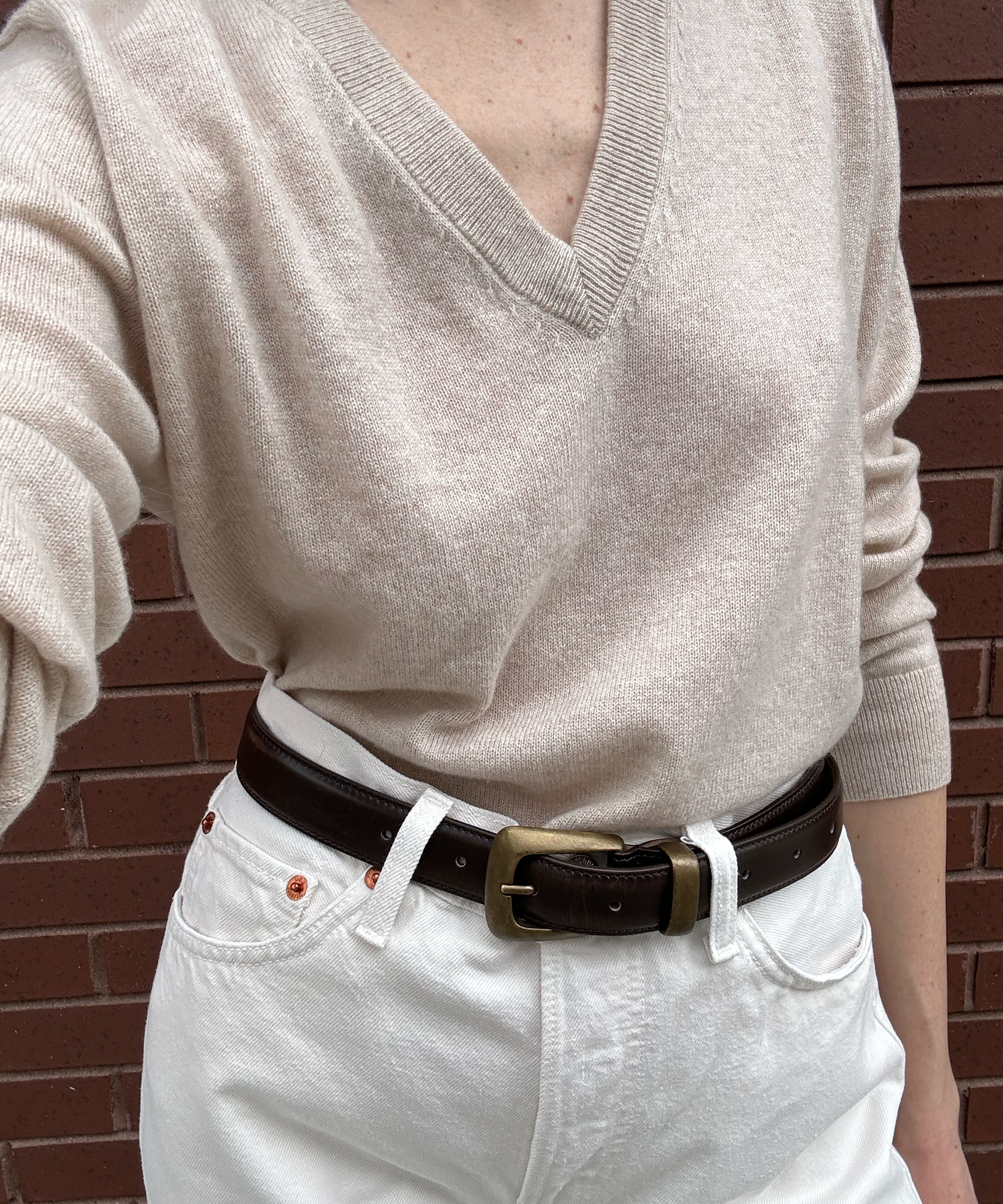 a oatmeal vneck cashmere sweater with a brown belt and creme jeans