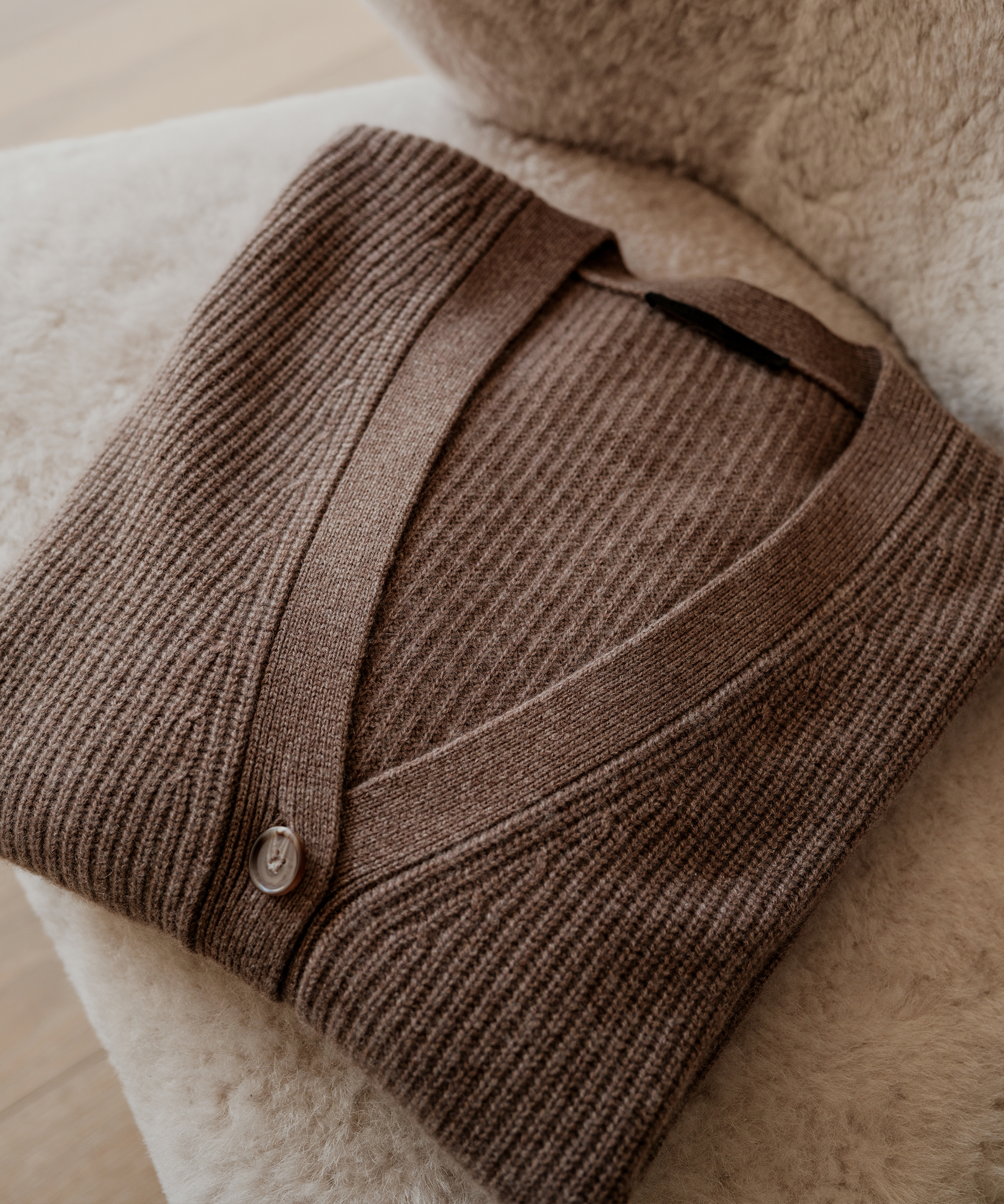 a shearling accent chair with a taupe cashmere cardigan folded