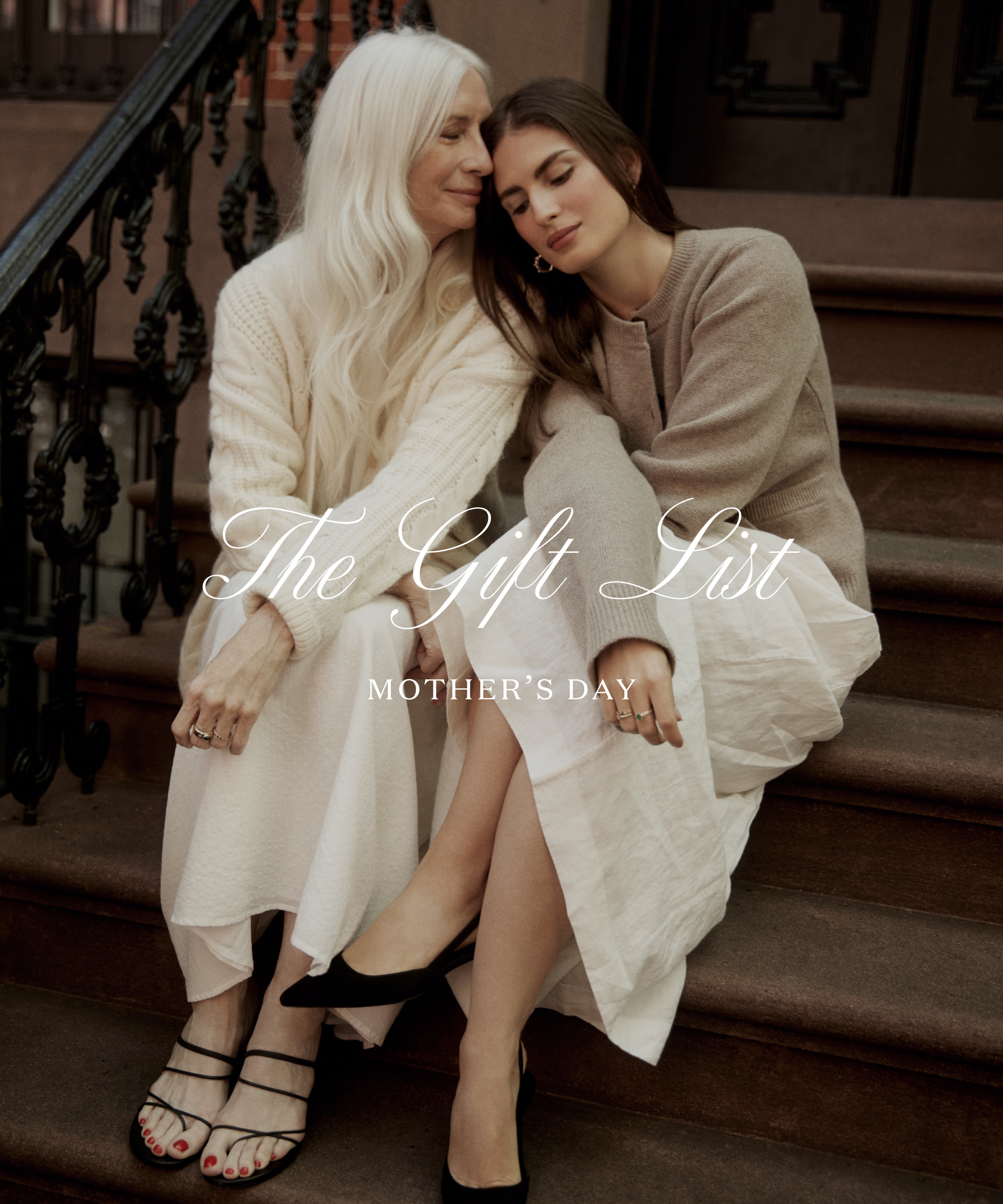 chloe and her mom sitting on stone steps wearing white skirts and cardigans leaning their heads together