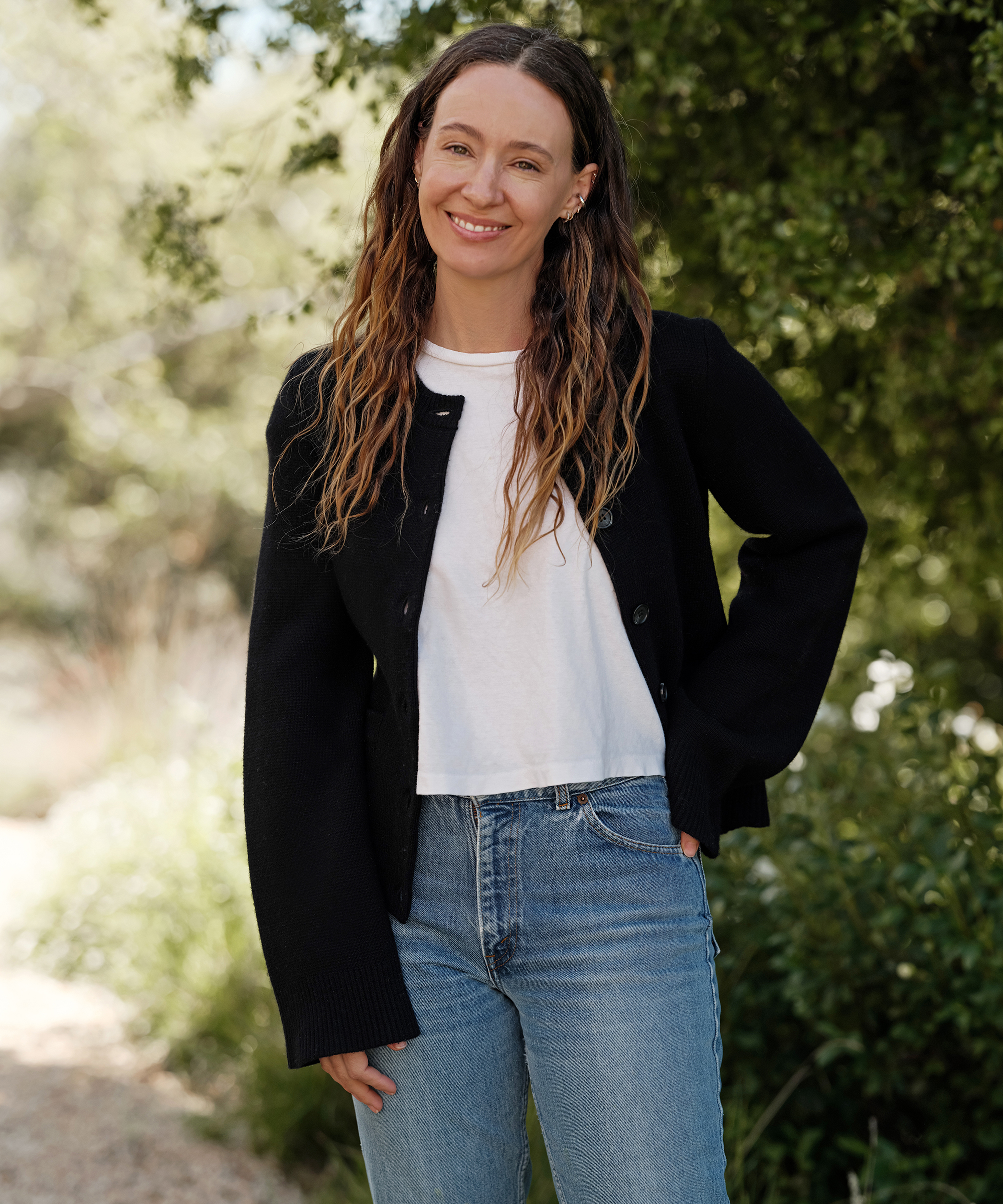 jenni wearing a white tee and black cardigan with jeans standing outside