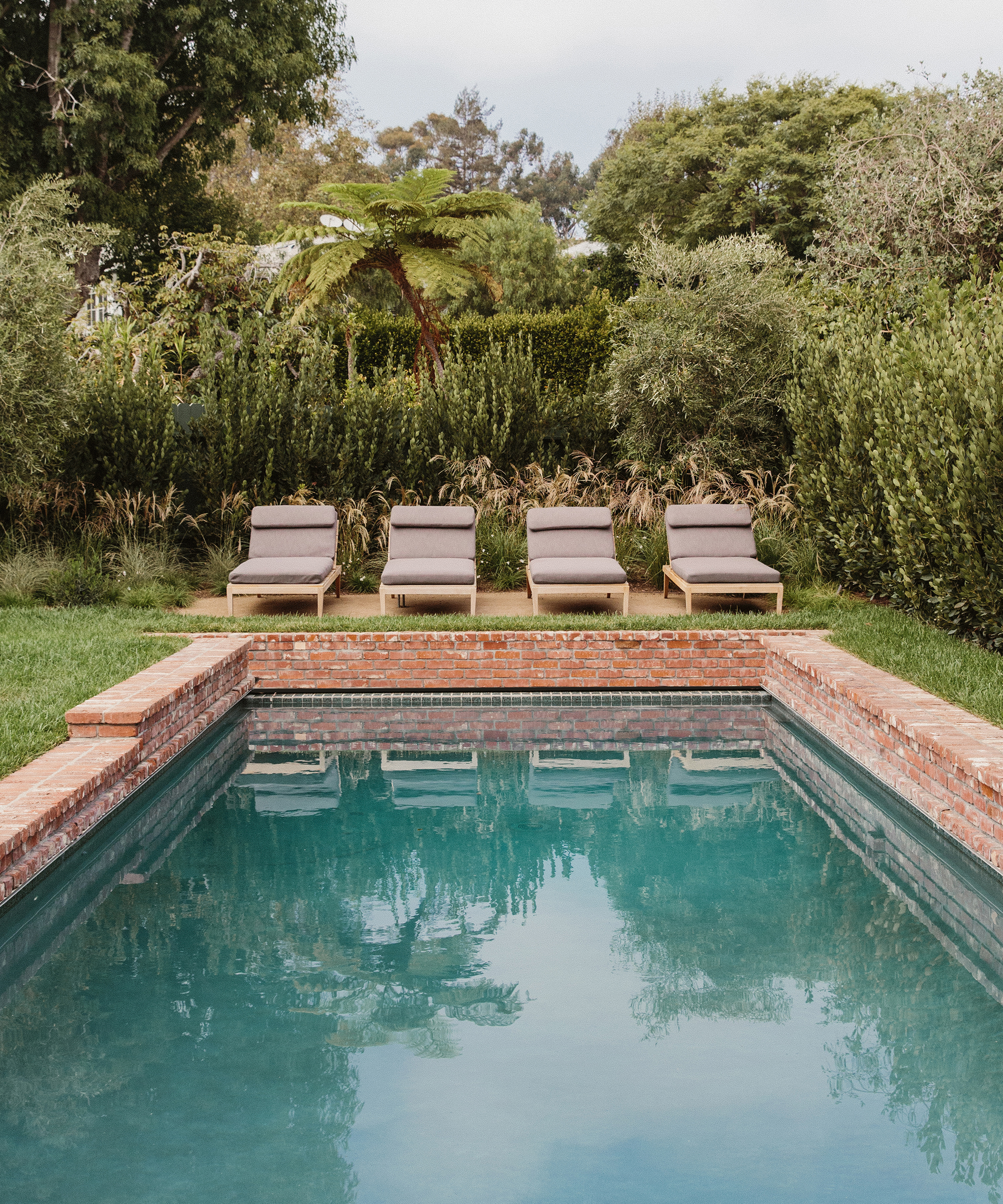 outdoor pool area with four charcoal lounge chairs next to a pool