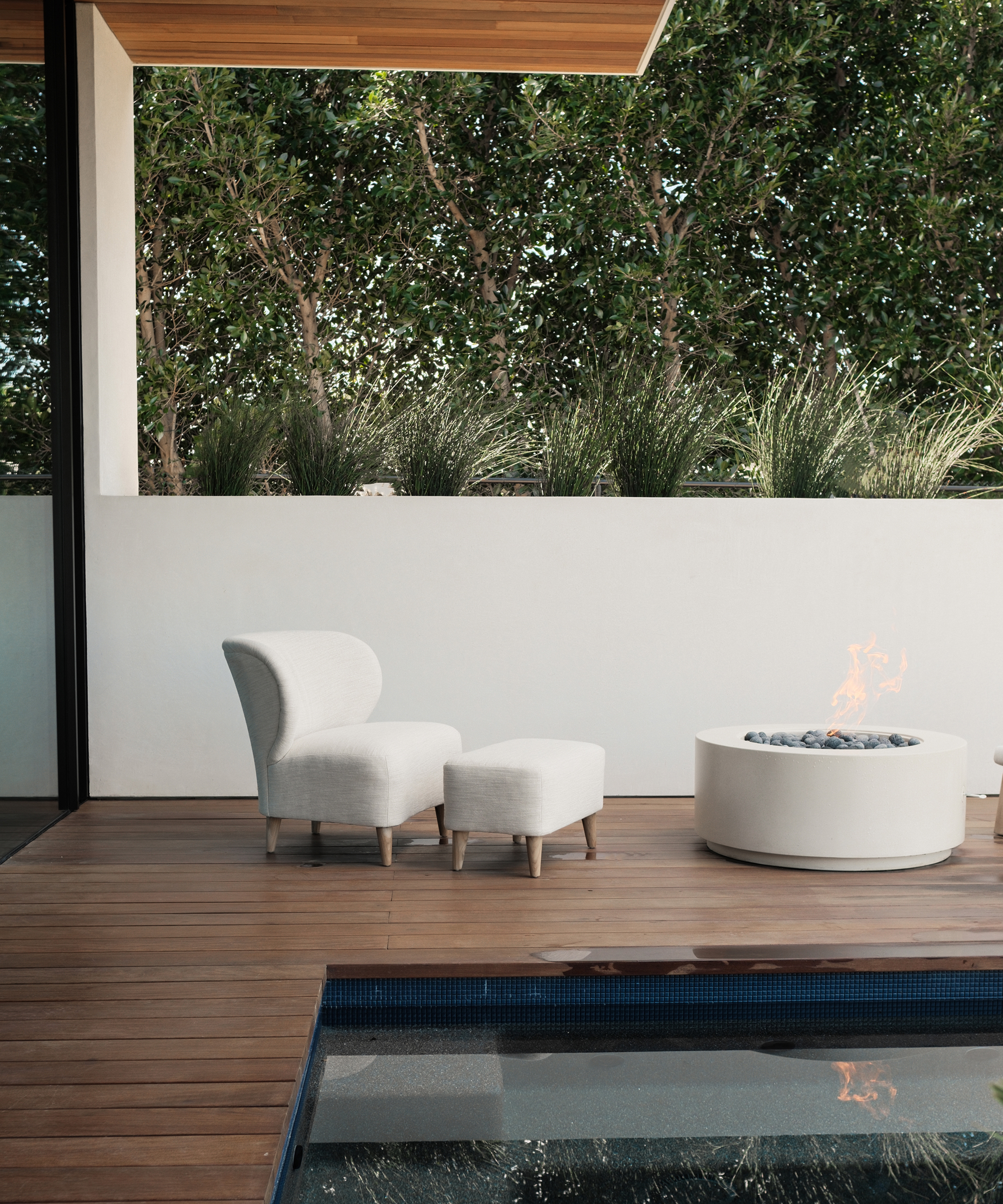a wooden outdoor patio with an outdoor brentwood accent chair next to a fire pit