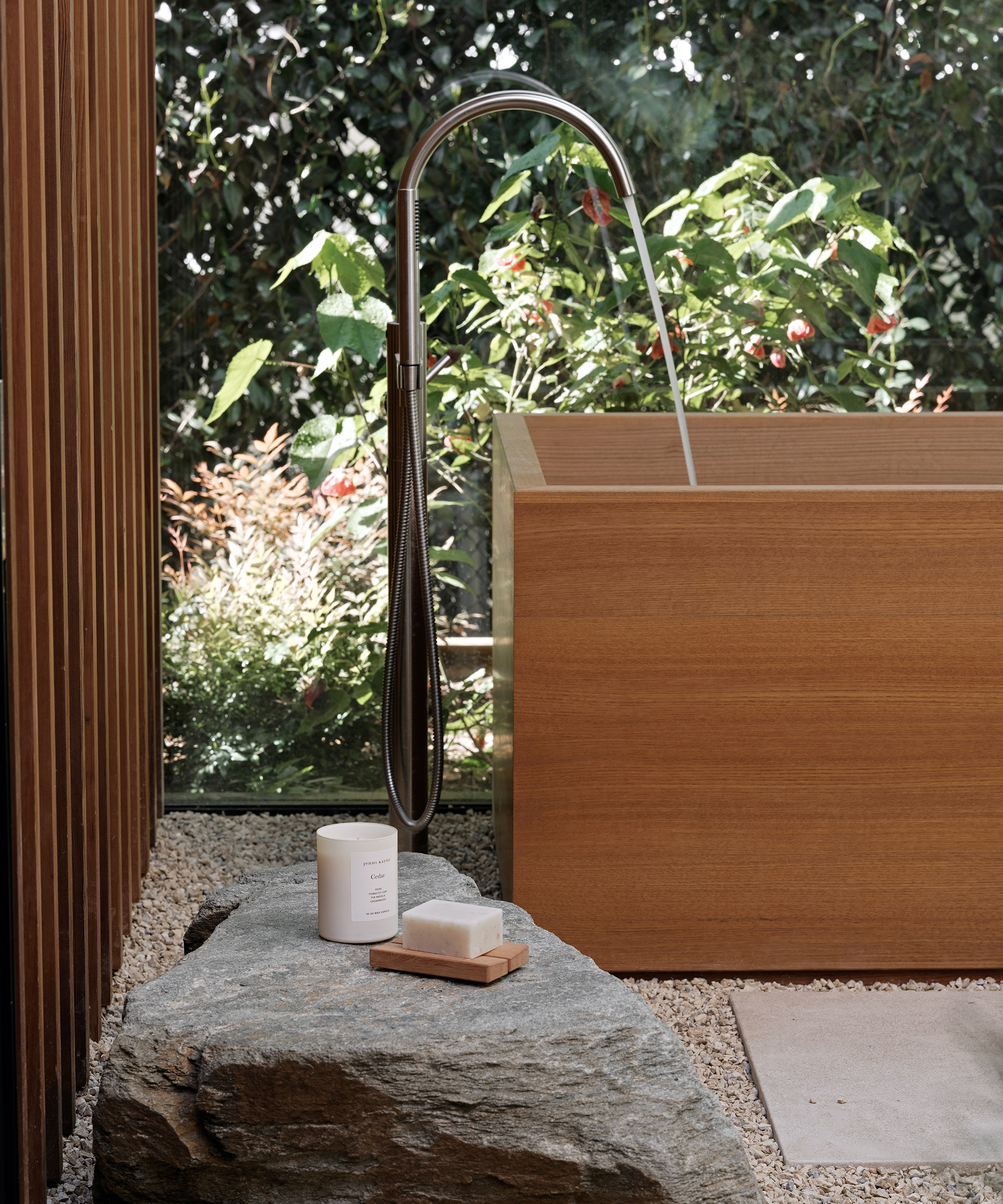 a wooden bathtub with water running next to a rock with a candle