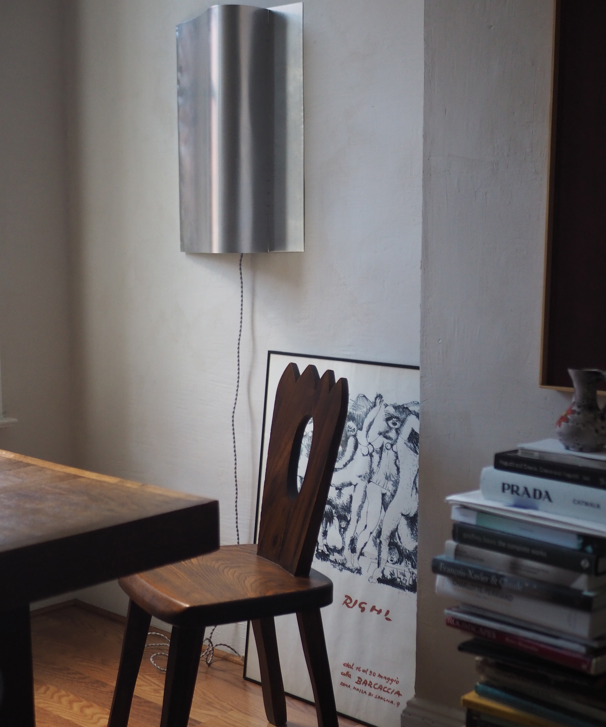 a wooden decorative accent chair next to a wooden table with a silver sconce