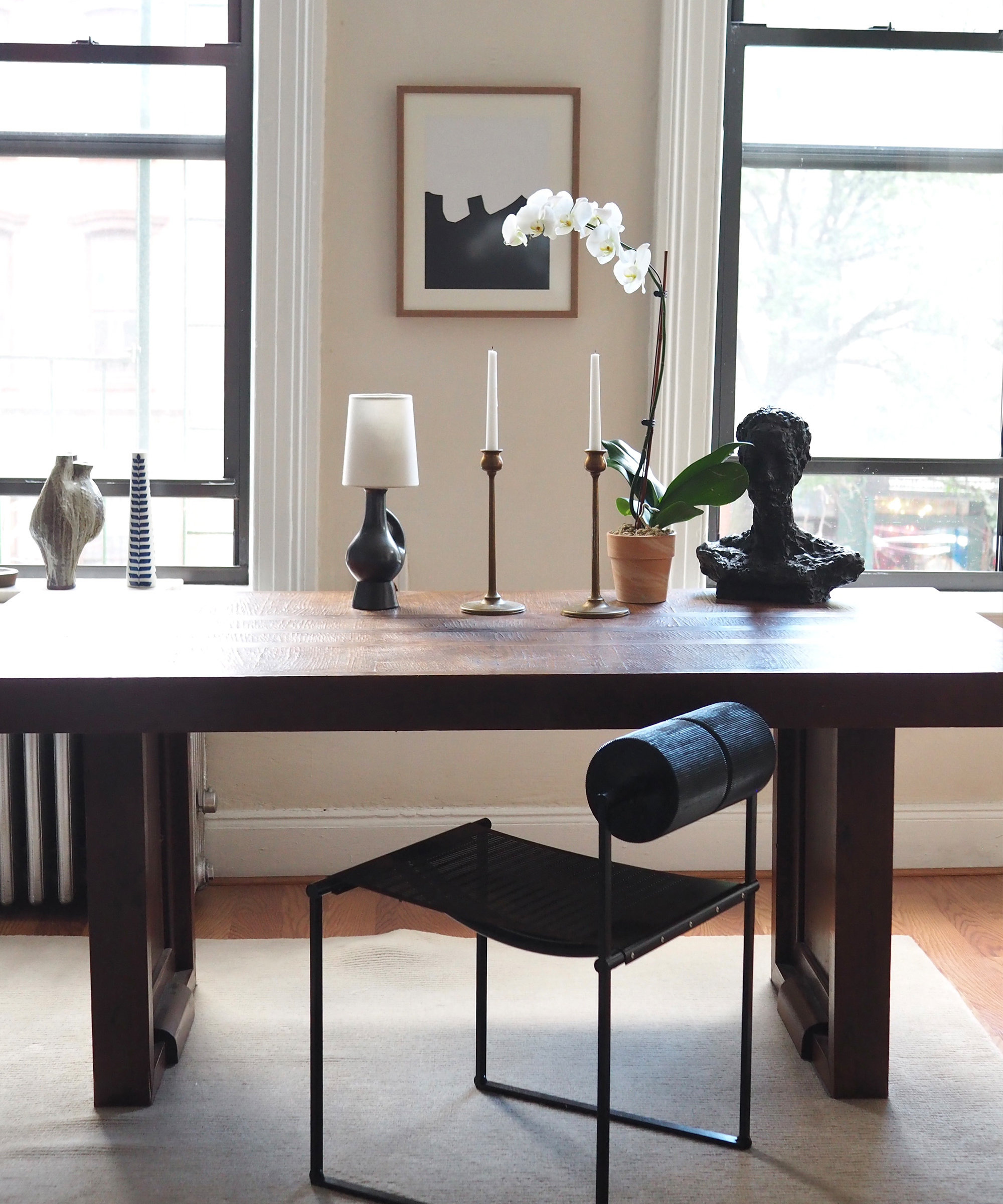 a wooden desk with a leather desk chair in front of two windows in an office