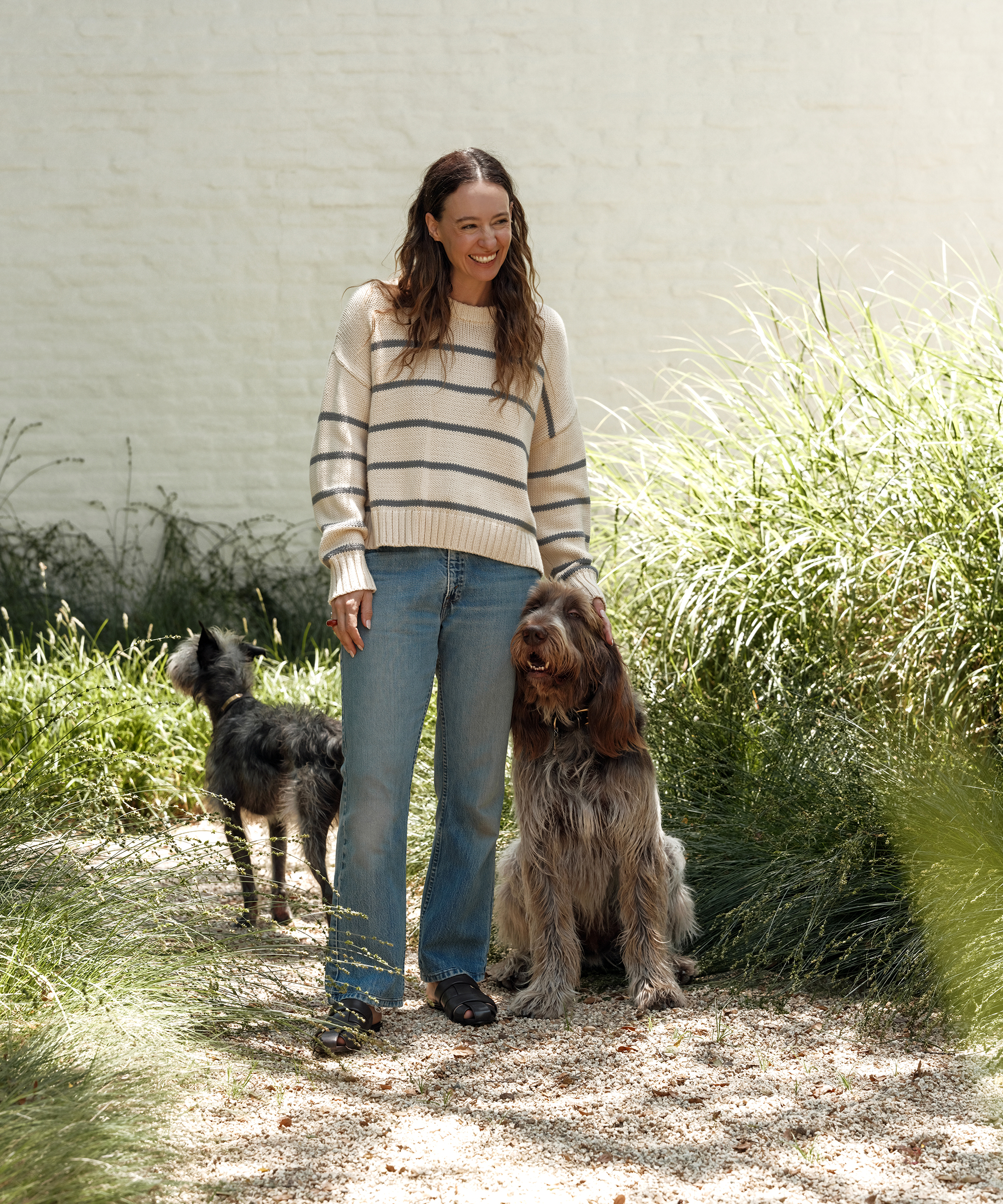 jenni wearing a cotton crewneck with ivory and dusty blue stripes standing next to her two dogs