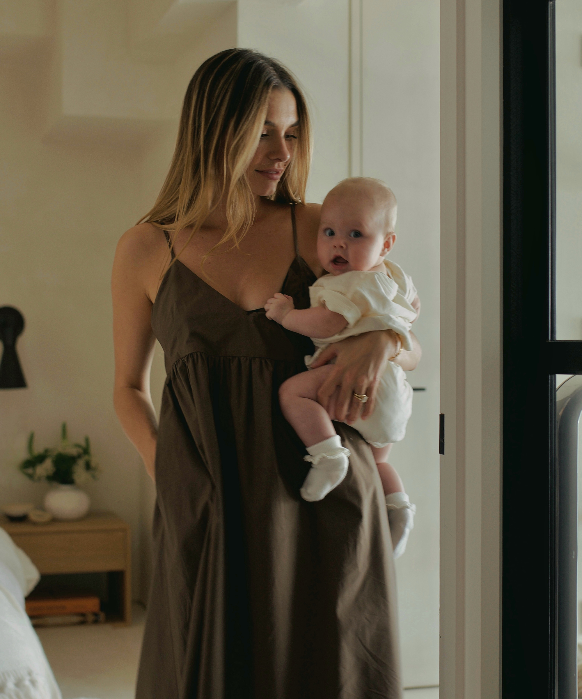 lauren burke in an olive dress holding her baby who is wearing a white vintage tee