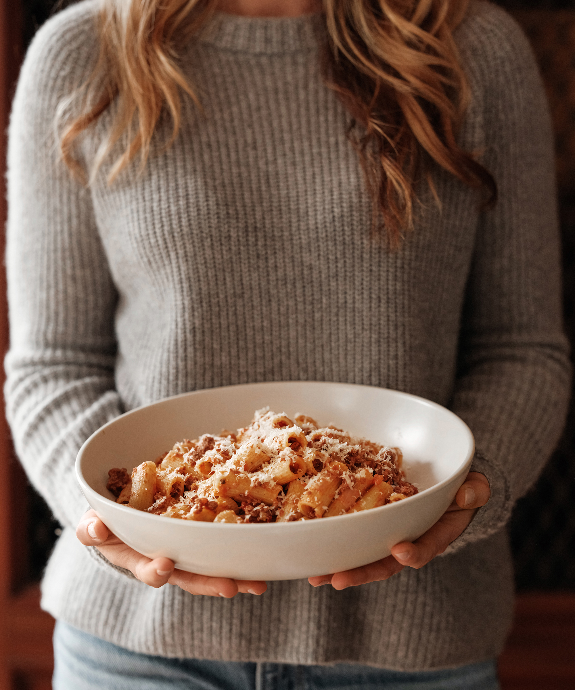 francesca holding a bowl of pasta with a grey sweater