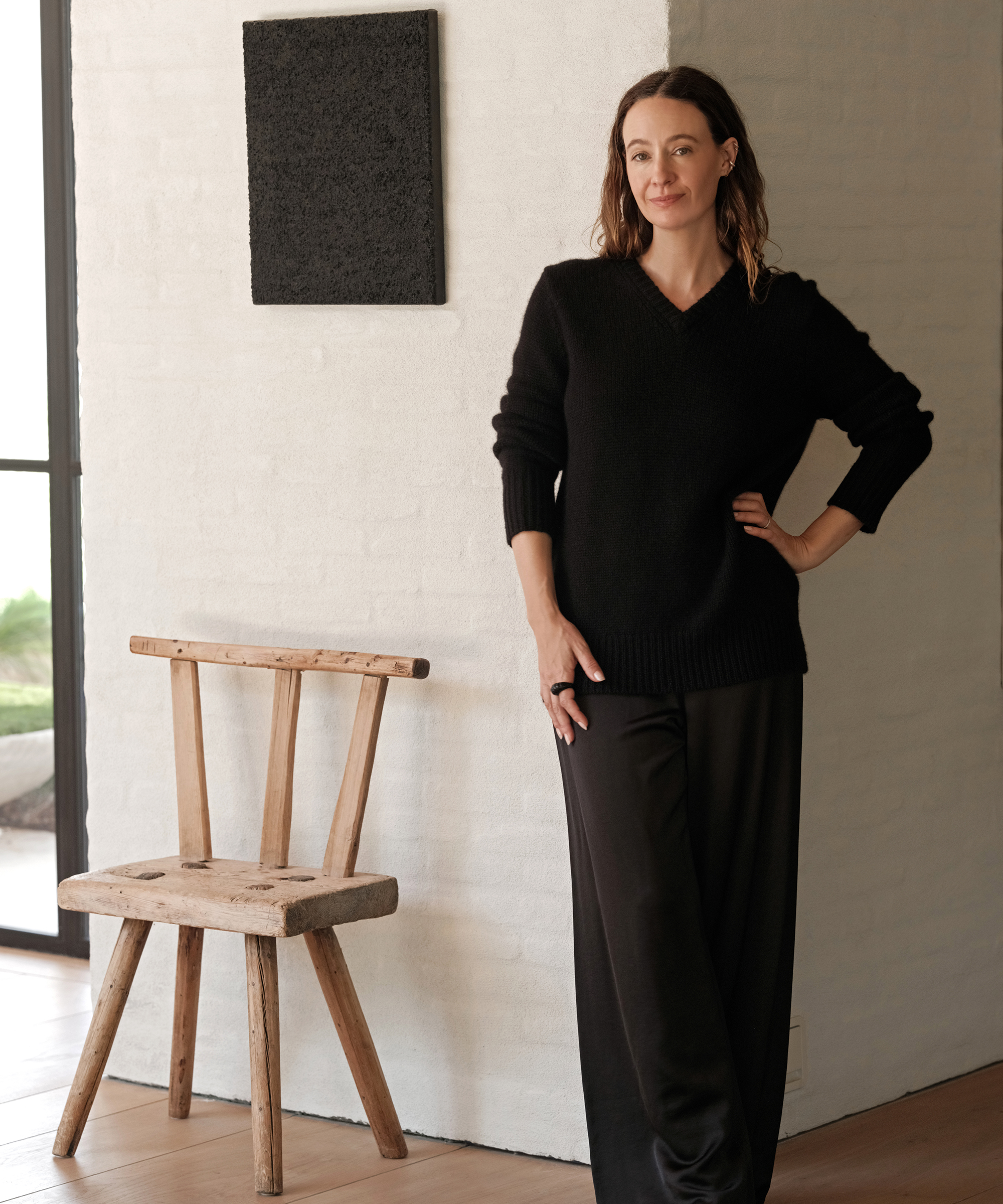 jenni in a black outfit with a black cashmere sweater and black demi pants next to a vintage chair