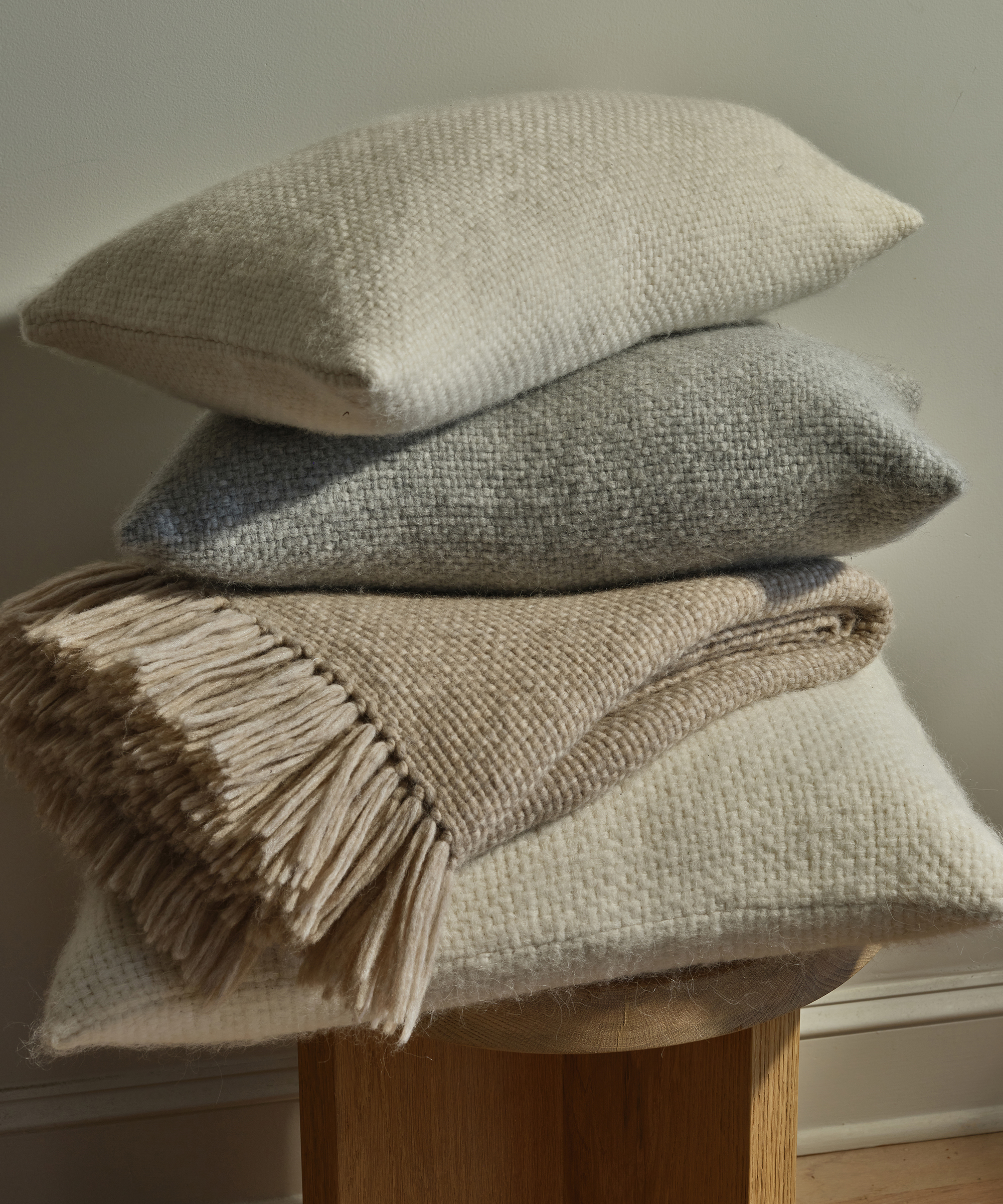 an alpaca basketweave throw and three basketweave pillows on a stool