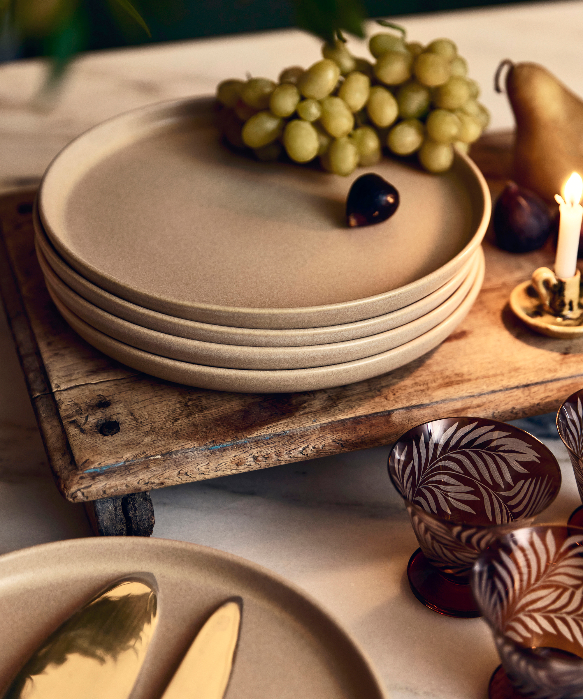 dinner plates in taupe stacked on a wooden board with grapes