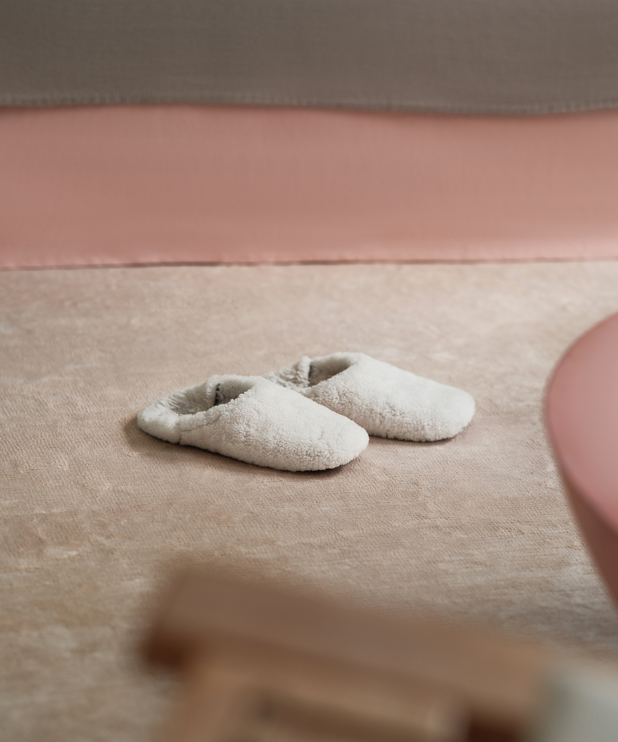 shearling slippers on an ivory rug in a bedroom