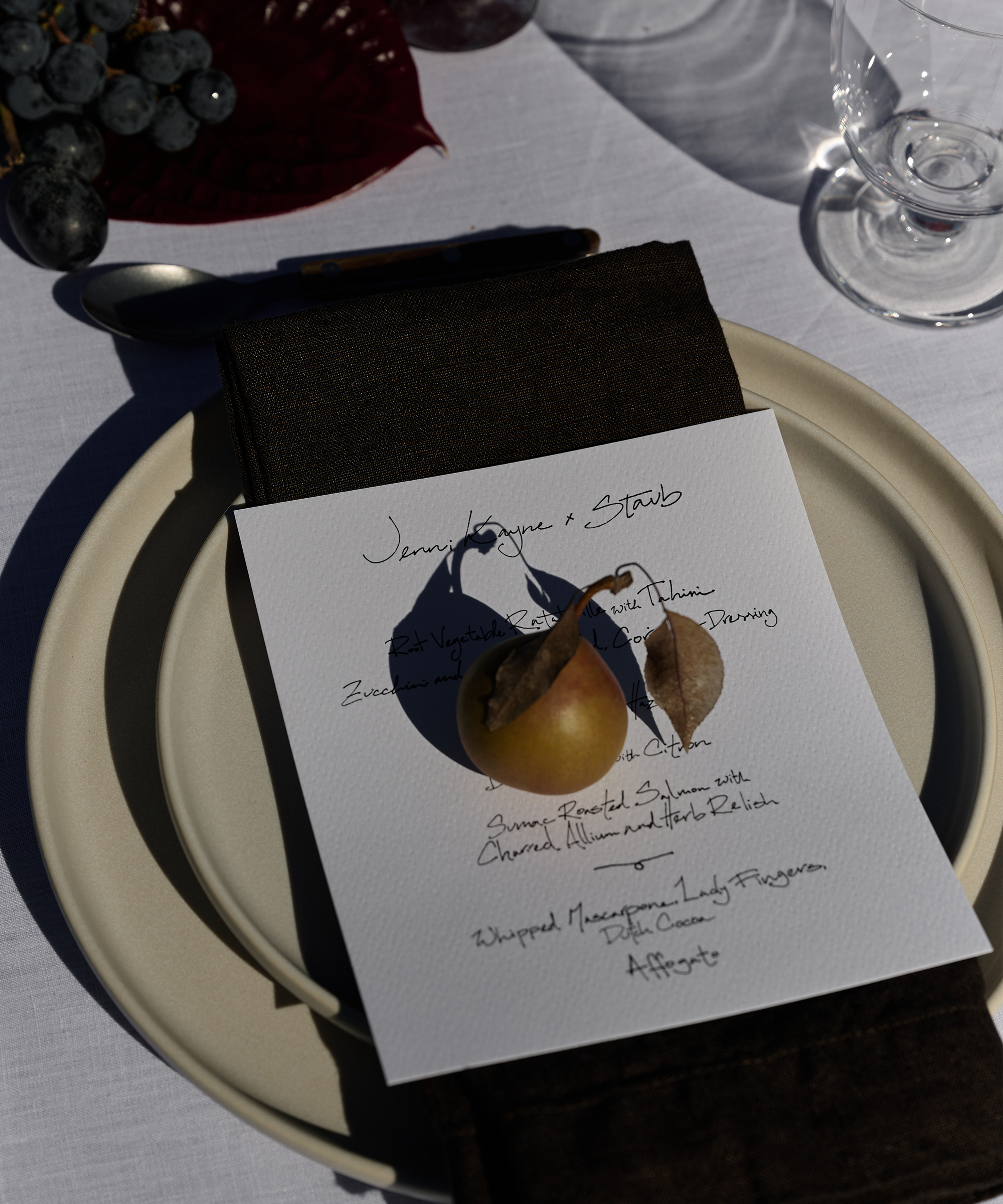 a table setting with taupe pacific dinnerware a menu and a pair atop
