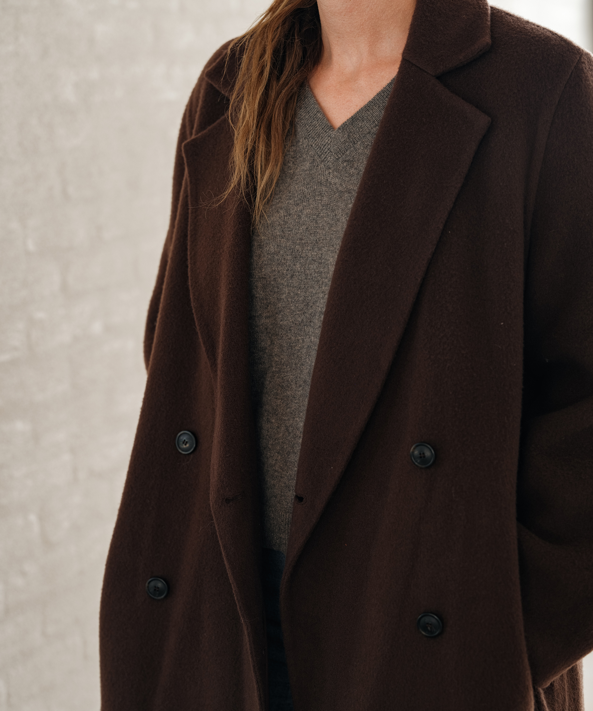 jenni wearing a brown coat with a grey vneck sweater