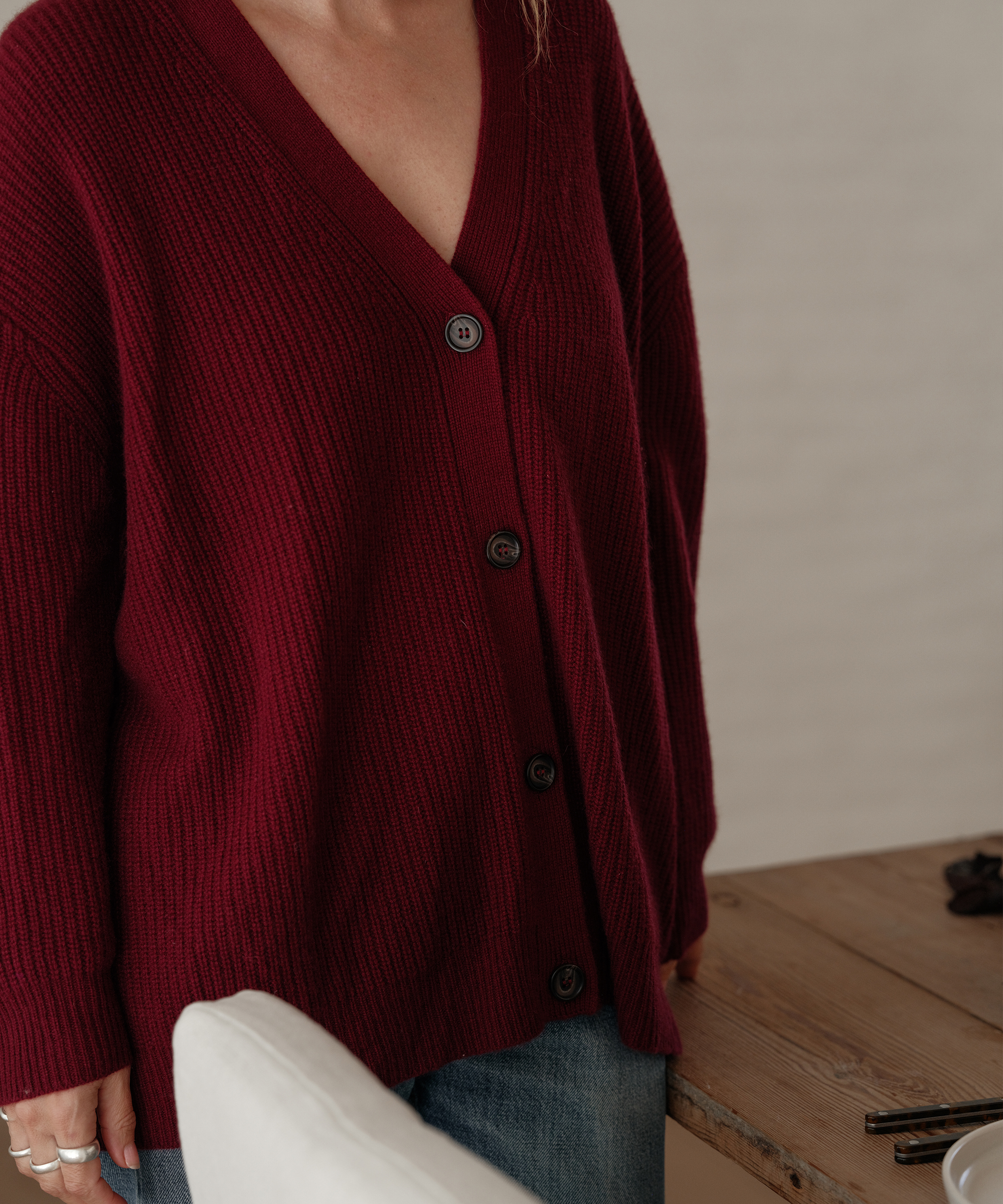jenni wearing a cashmere cardigan in a deep red standing inside