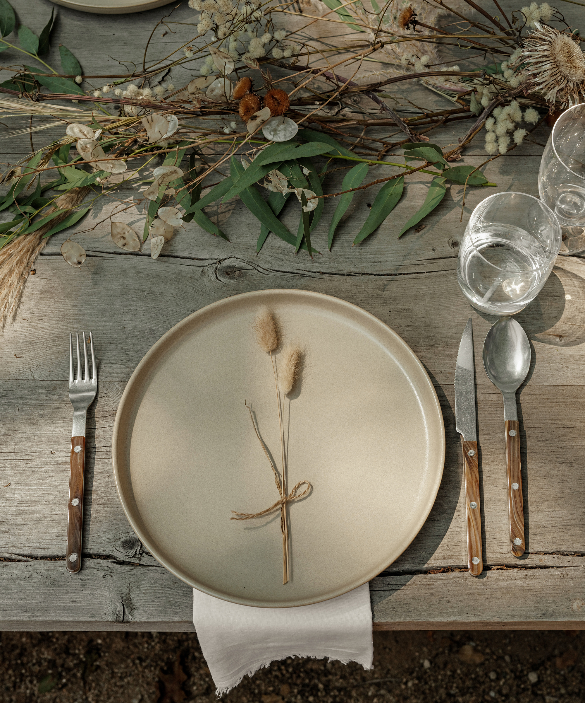 a taupe dinner plate and buffalo cutlery on a wooden dining table