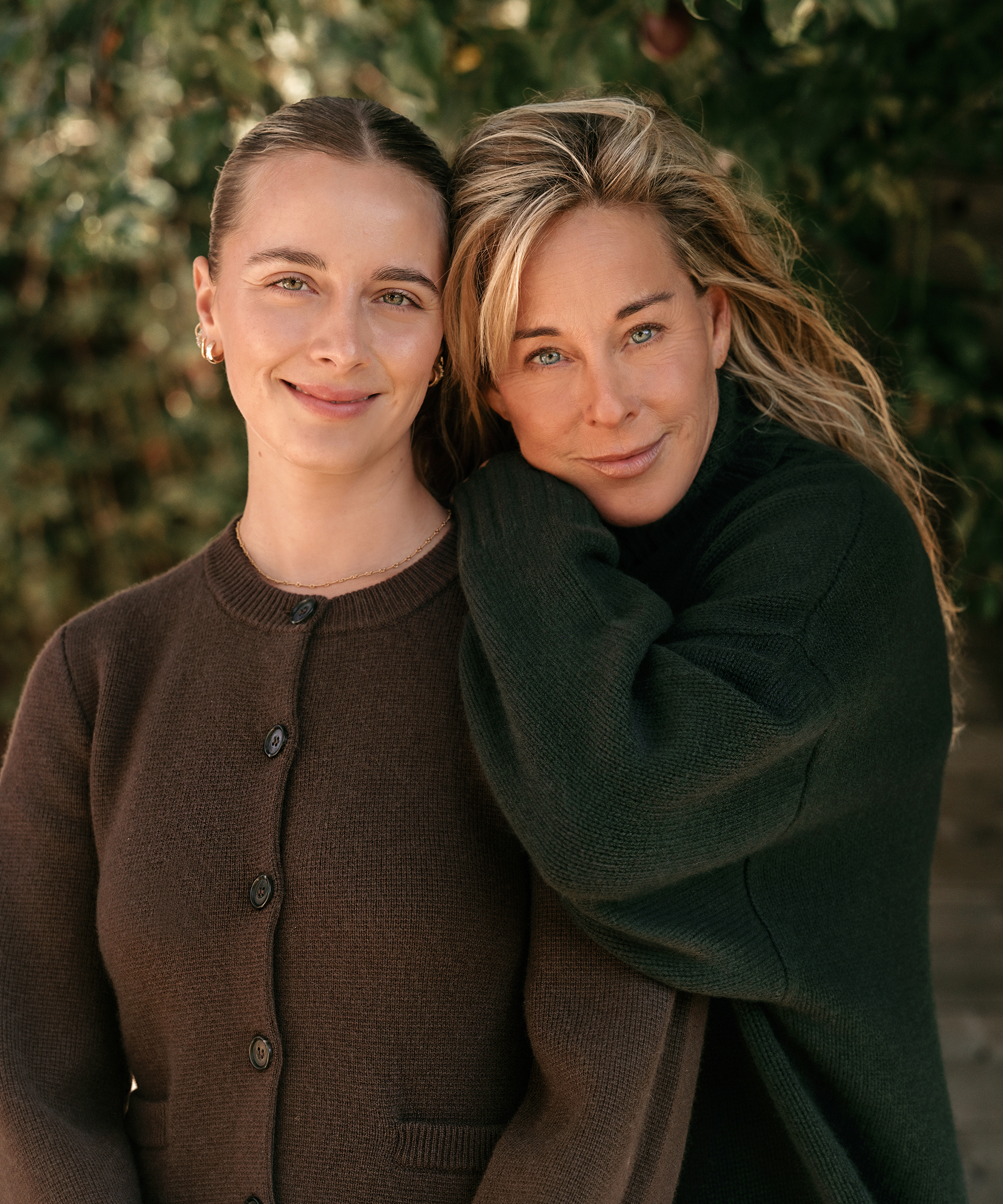 sarah wearing a brown cardigan posing next to her mom in a forest green turtleneck