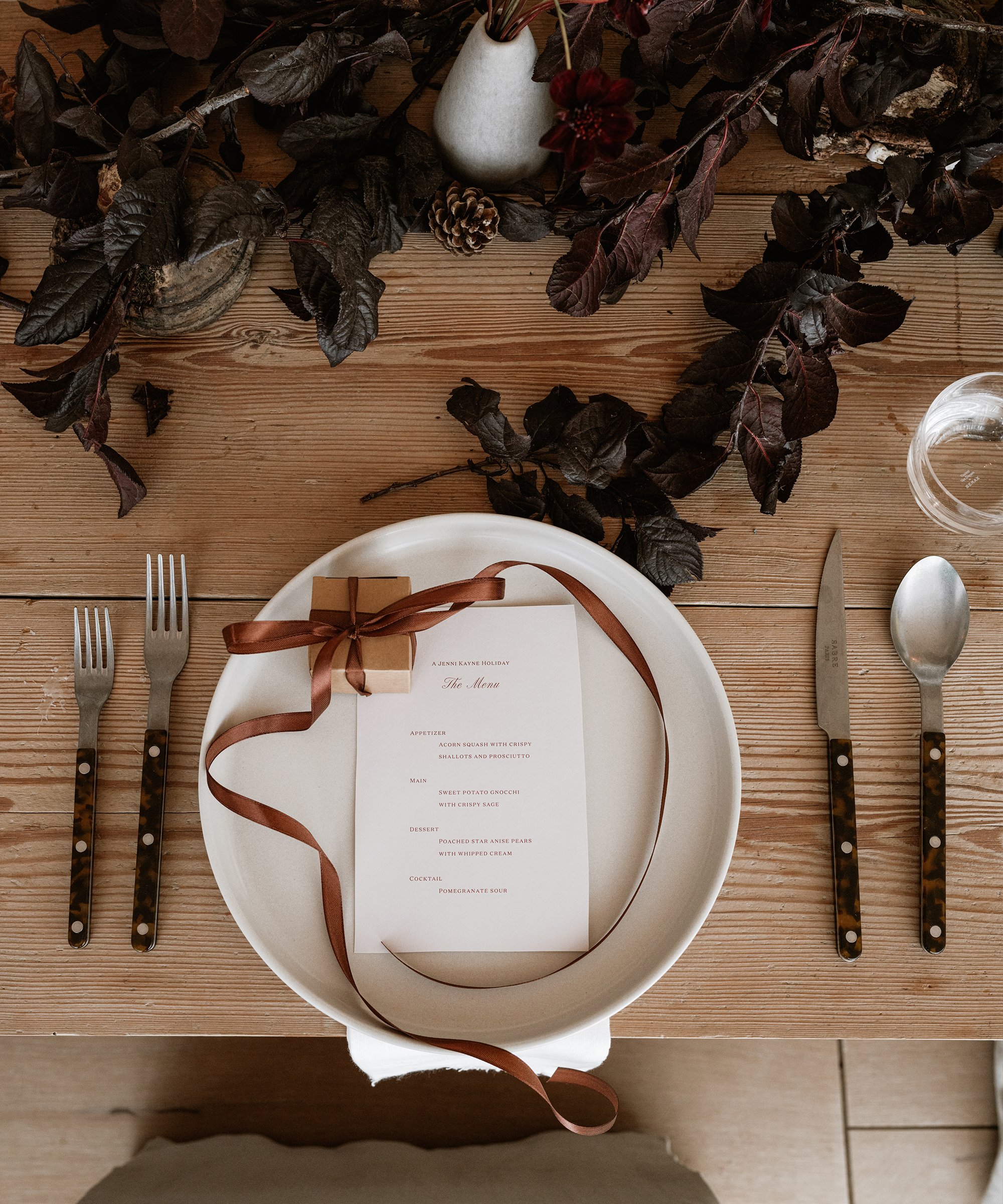 a dinner table with an ivory plate and a menu and a present