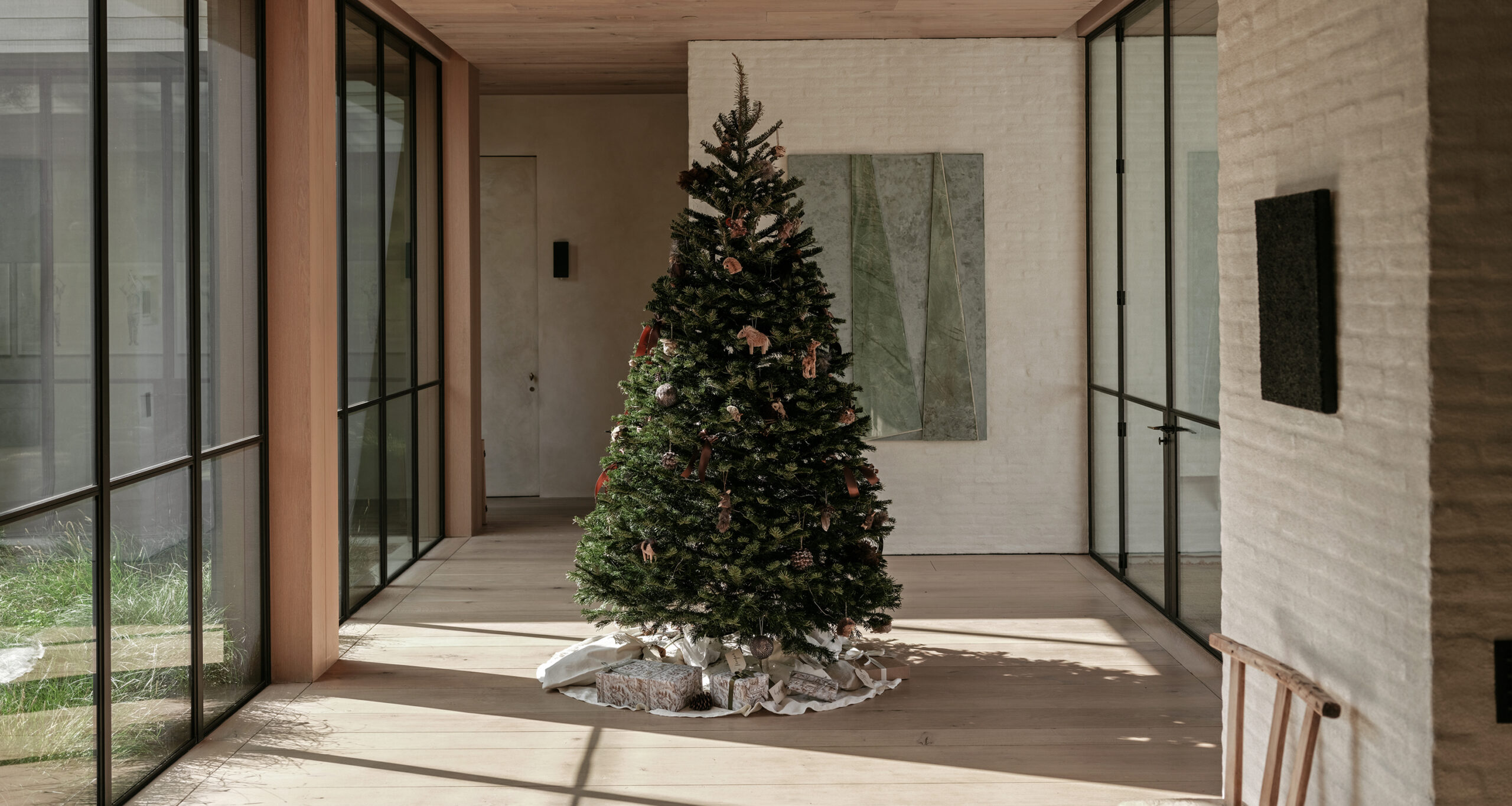 a hallway with a christmas tree in the middle with a linen tree skirt