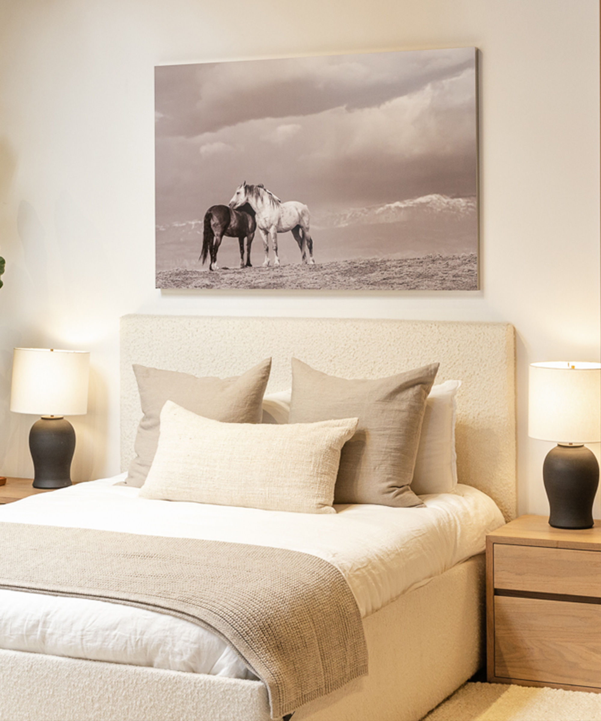 an ivory boucle upholstered bed with a horse photograph hanging above
