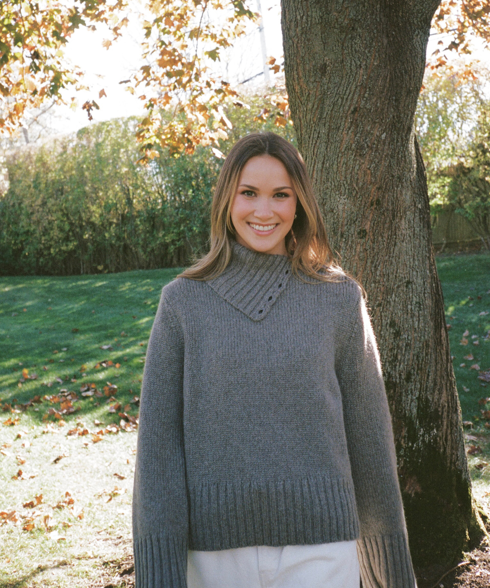 meredith standing outside next to a tree in a taupe cashmere sweater