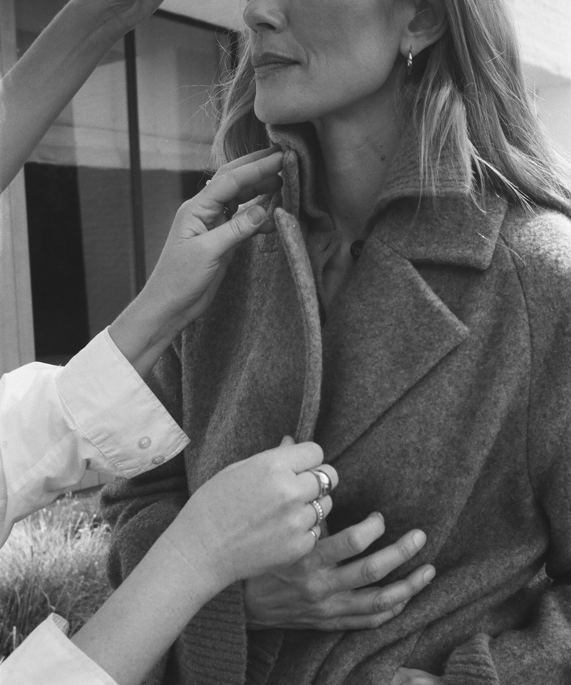 two hands adjusting a coat on a woman model
