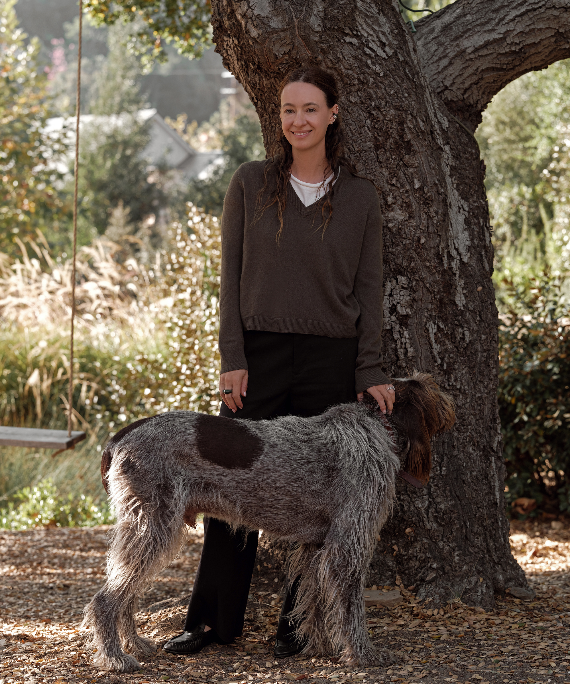 jenni in a greenstone v-neck cashmere sweater with a white tee underneath next to her dog