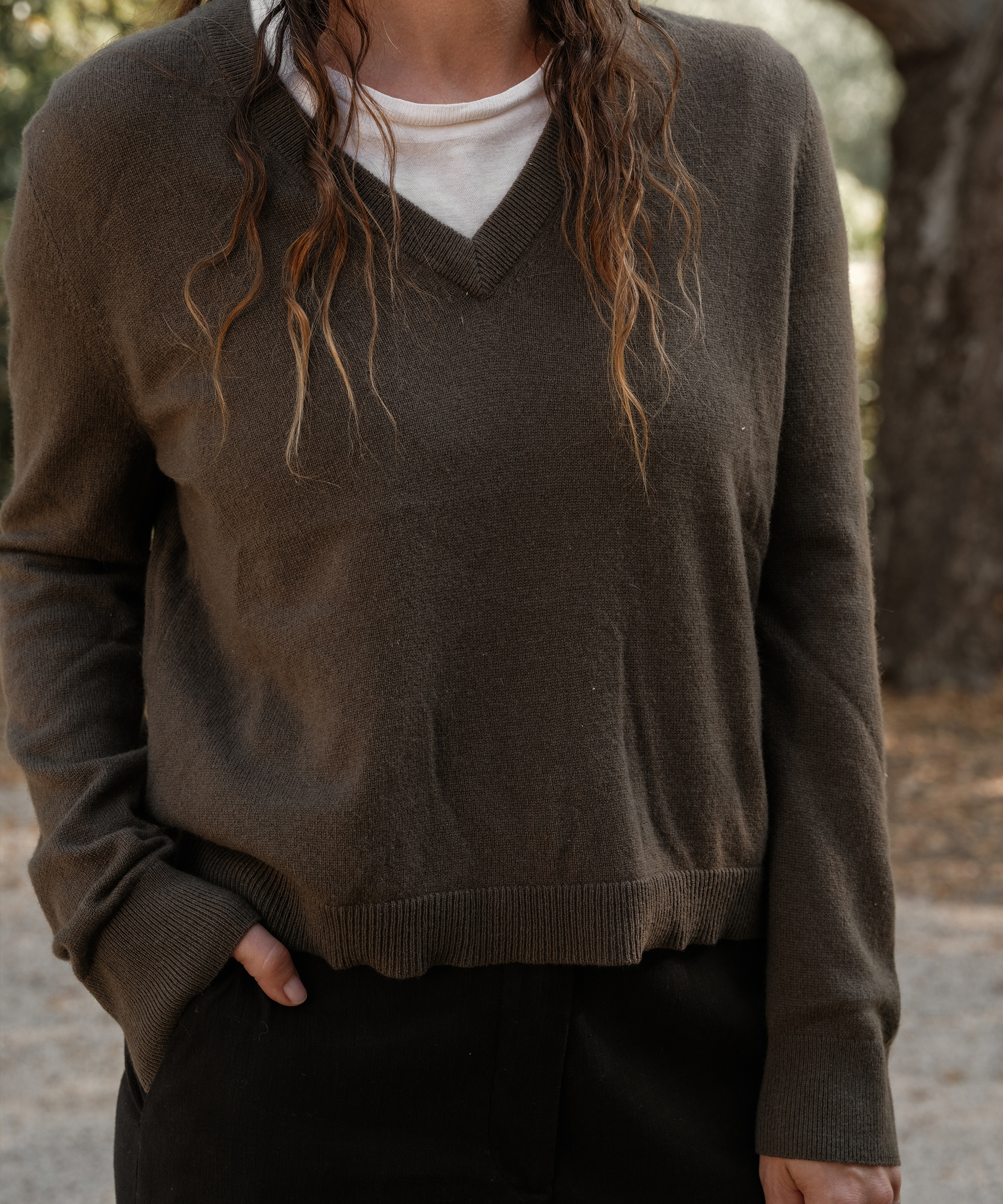 a woman wearng a green vneck cashmere sweater with a white tee layered underneath
