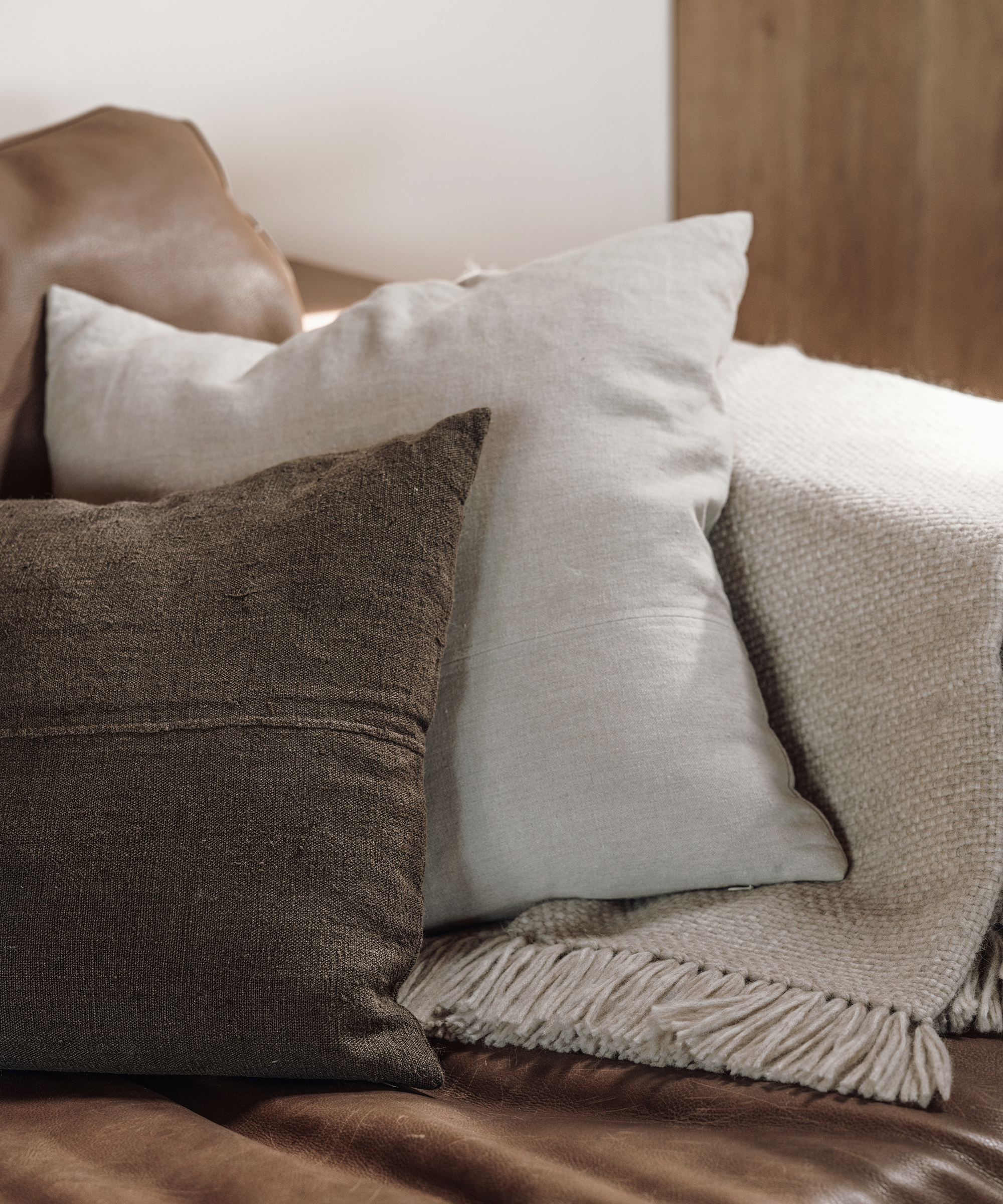 two accent pillows on a couch with a taupe alpaca basketweave throw