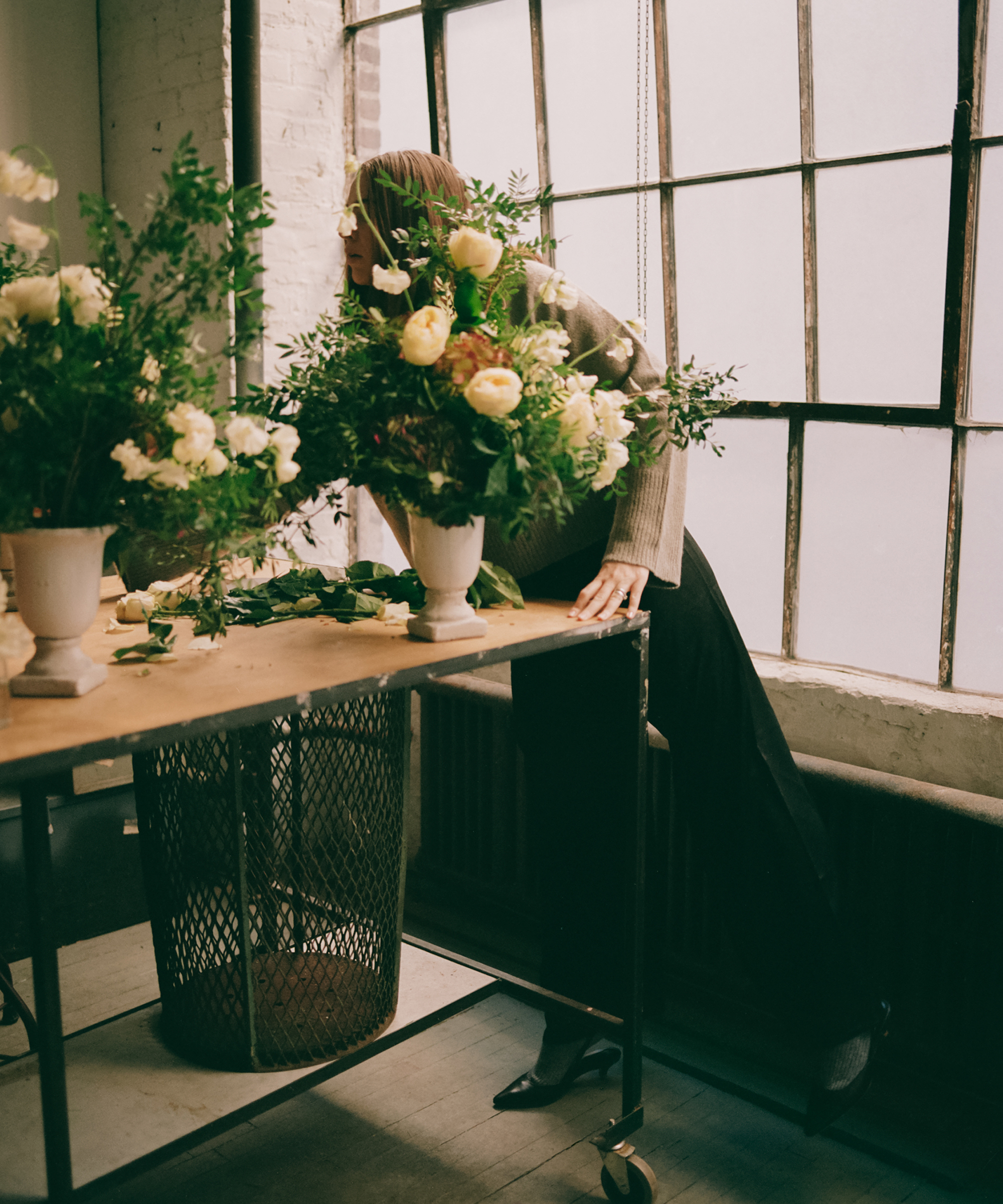 a flower shop with white bouquets and a women wearing silk trousers and a grey cashmere sweater