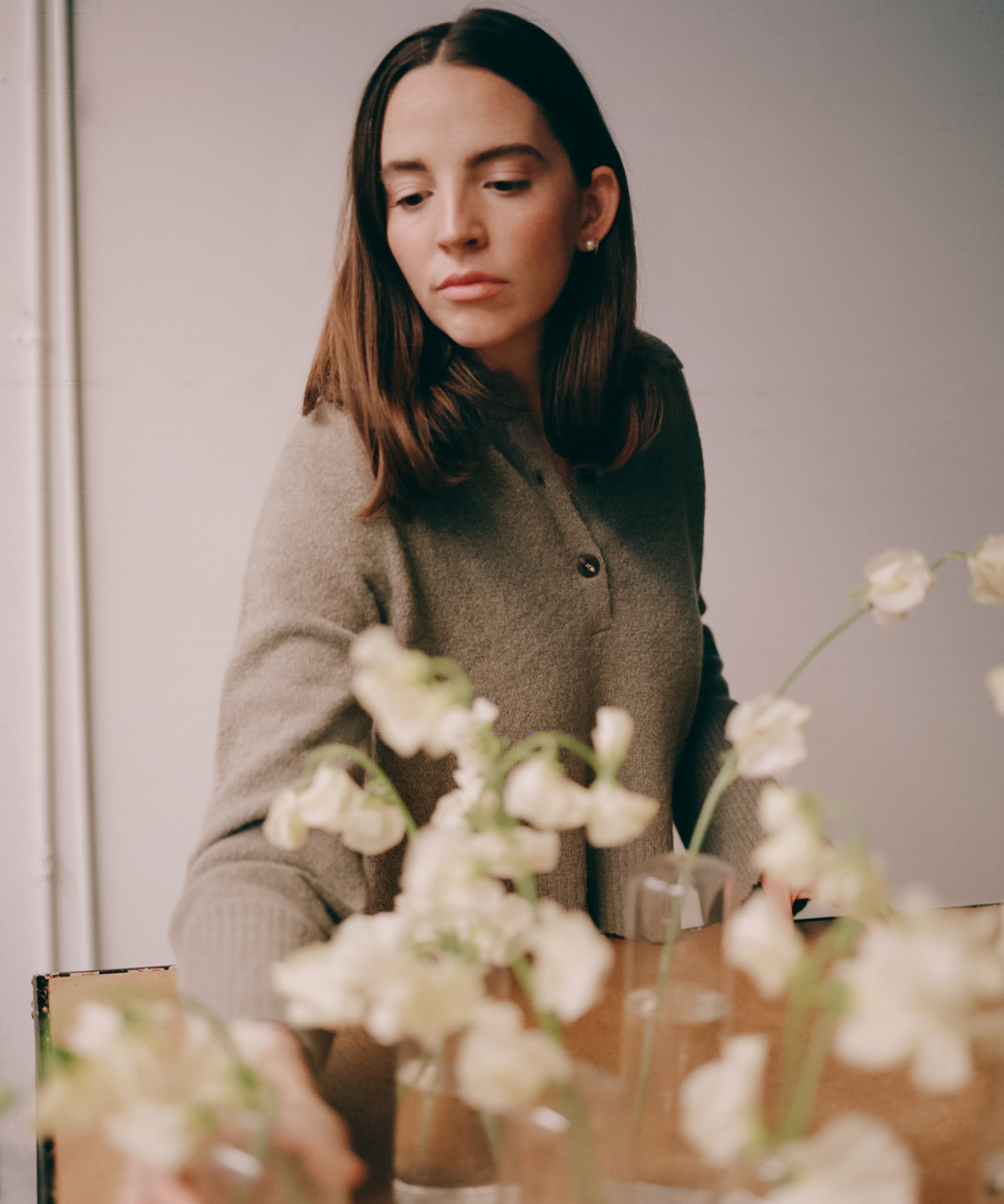 molly wearing a pewter sweater leaning in to grab a floral arrangement