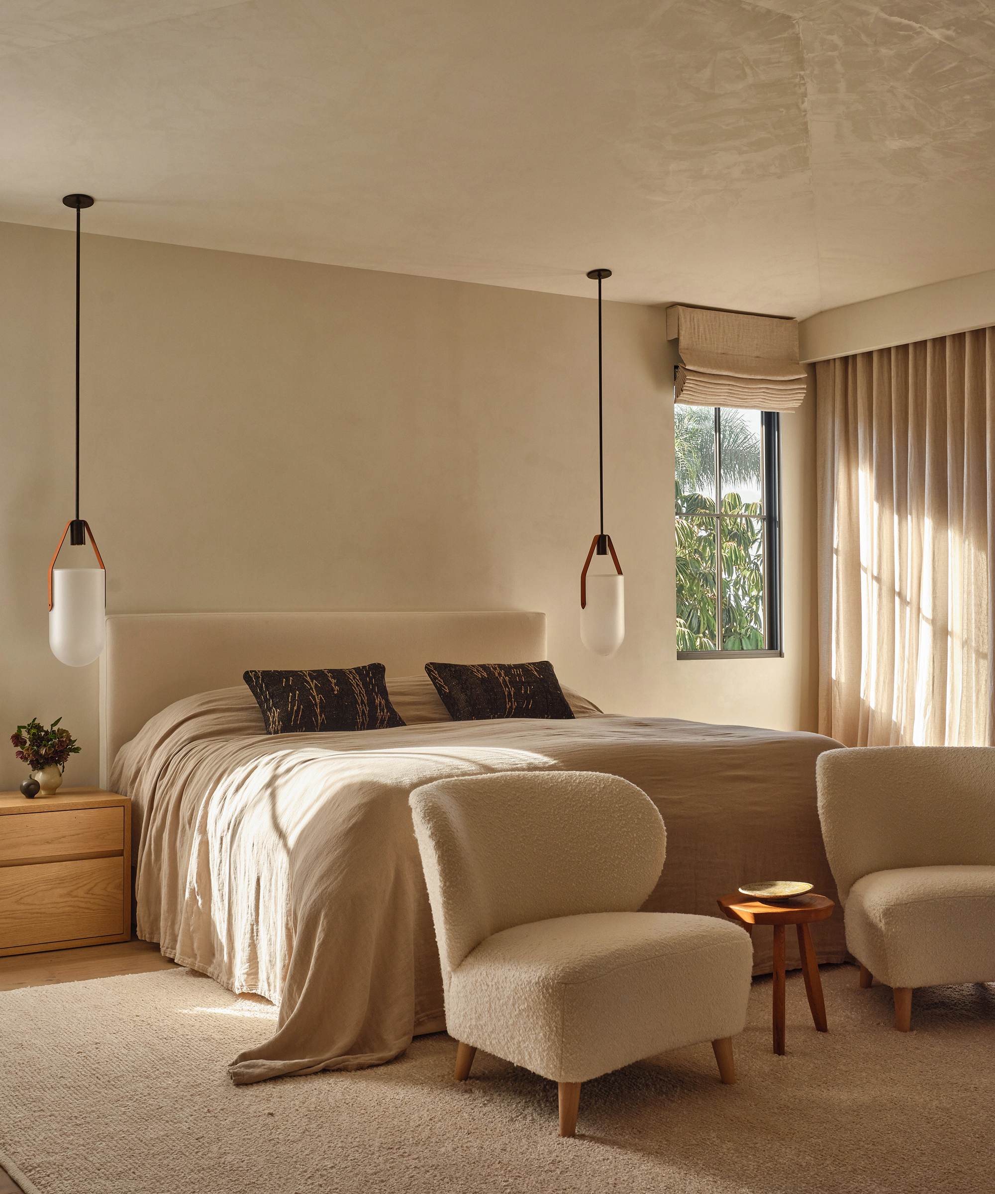 a bedroom with two accent chairs and a creme upholstered bed