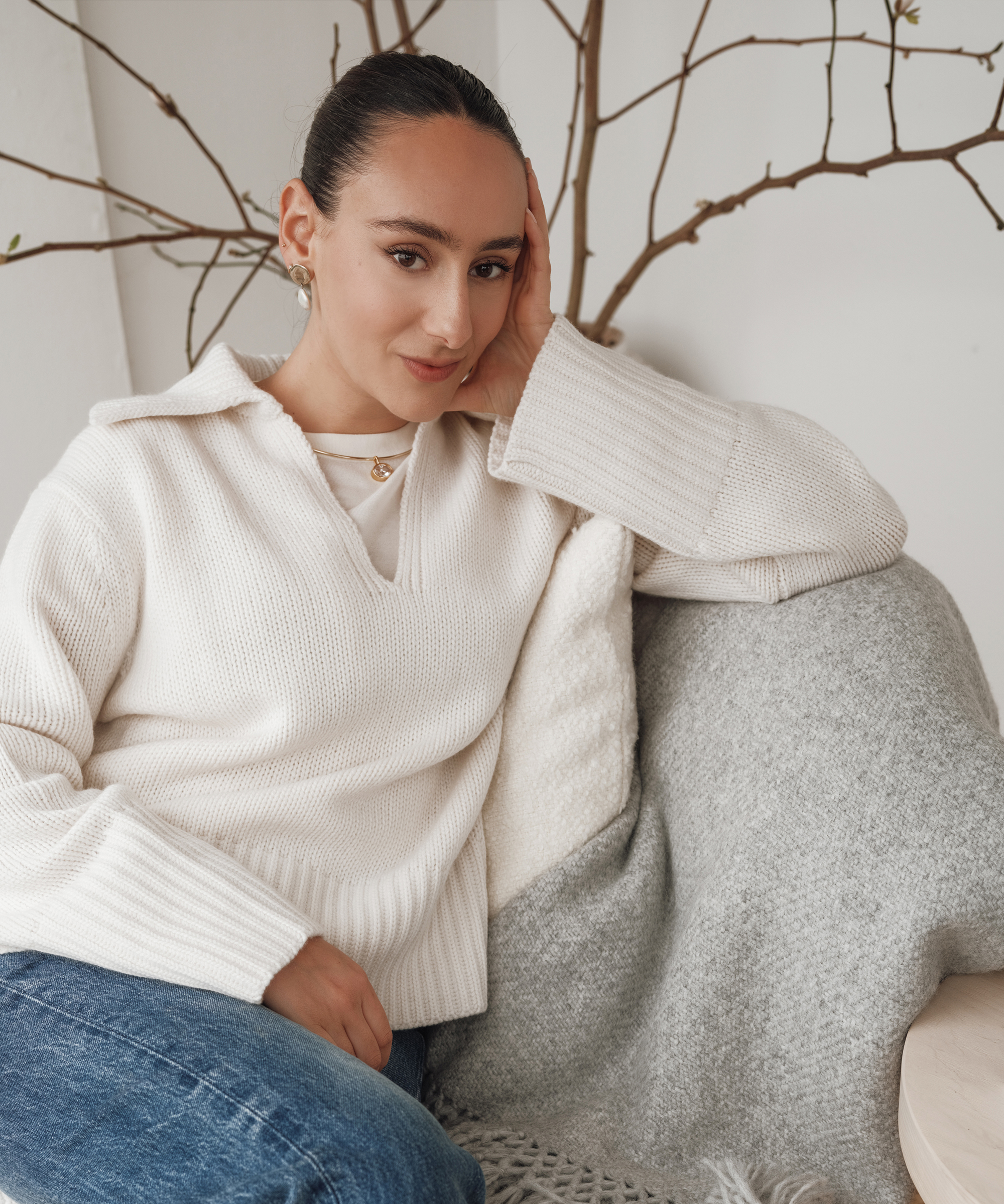 julia sitting on a boucle chair wearing an ivory cashmere sweater