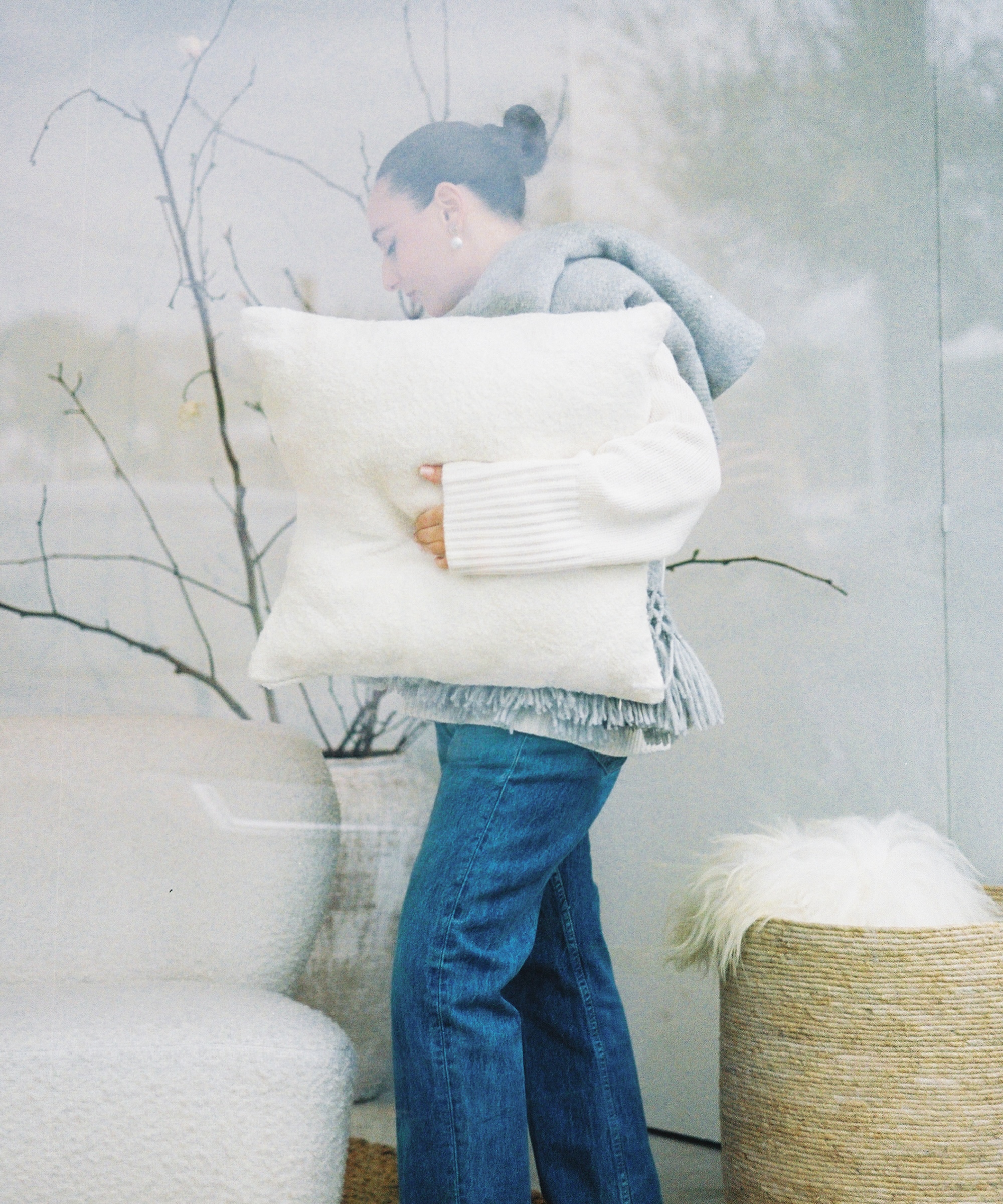 julia holding an ivory alpaca basketweave pillow inside a window display
