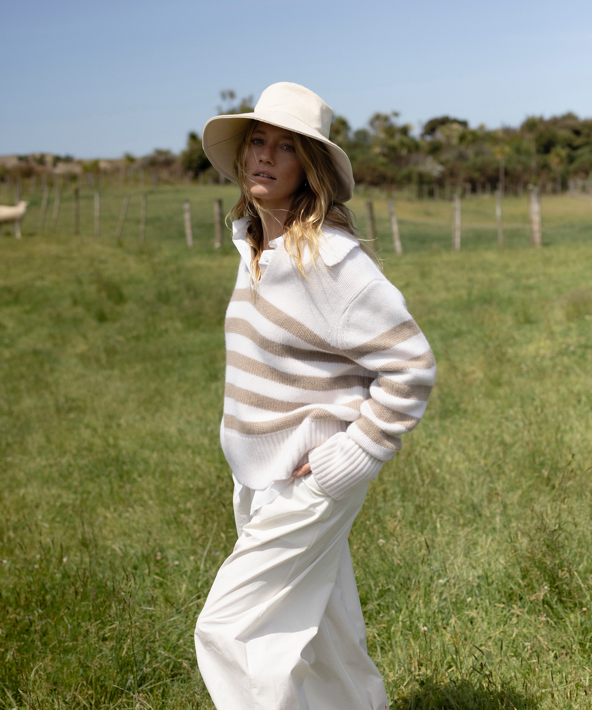 a woman wearing a cashmere striped polo and ivory trousers in gass