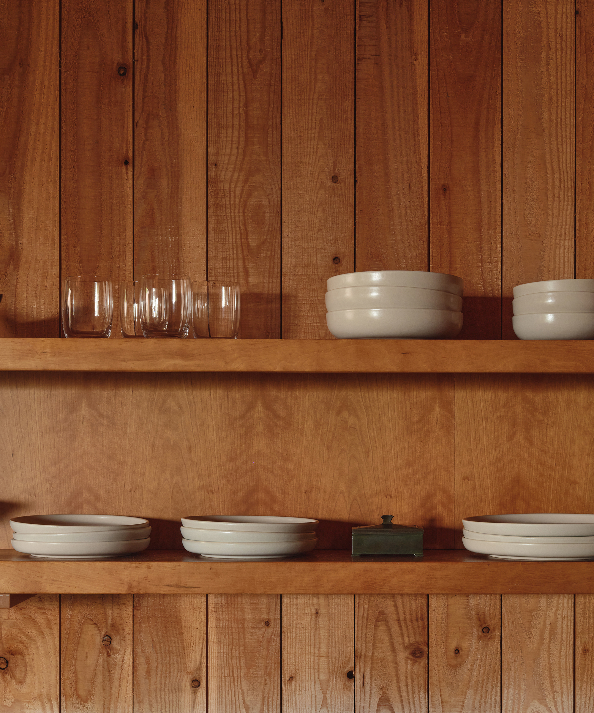 a kitchen with wooden paneling and open shelving with kitchen plates and bowls