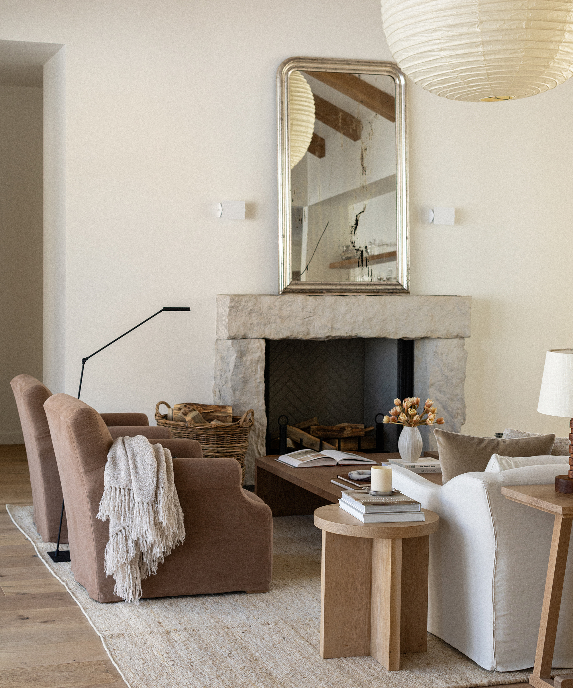 a living room with two linen brown accent chairs and a stone fireplace