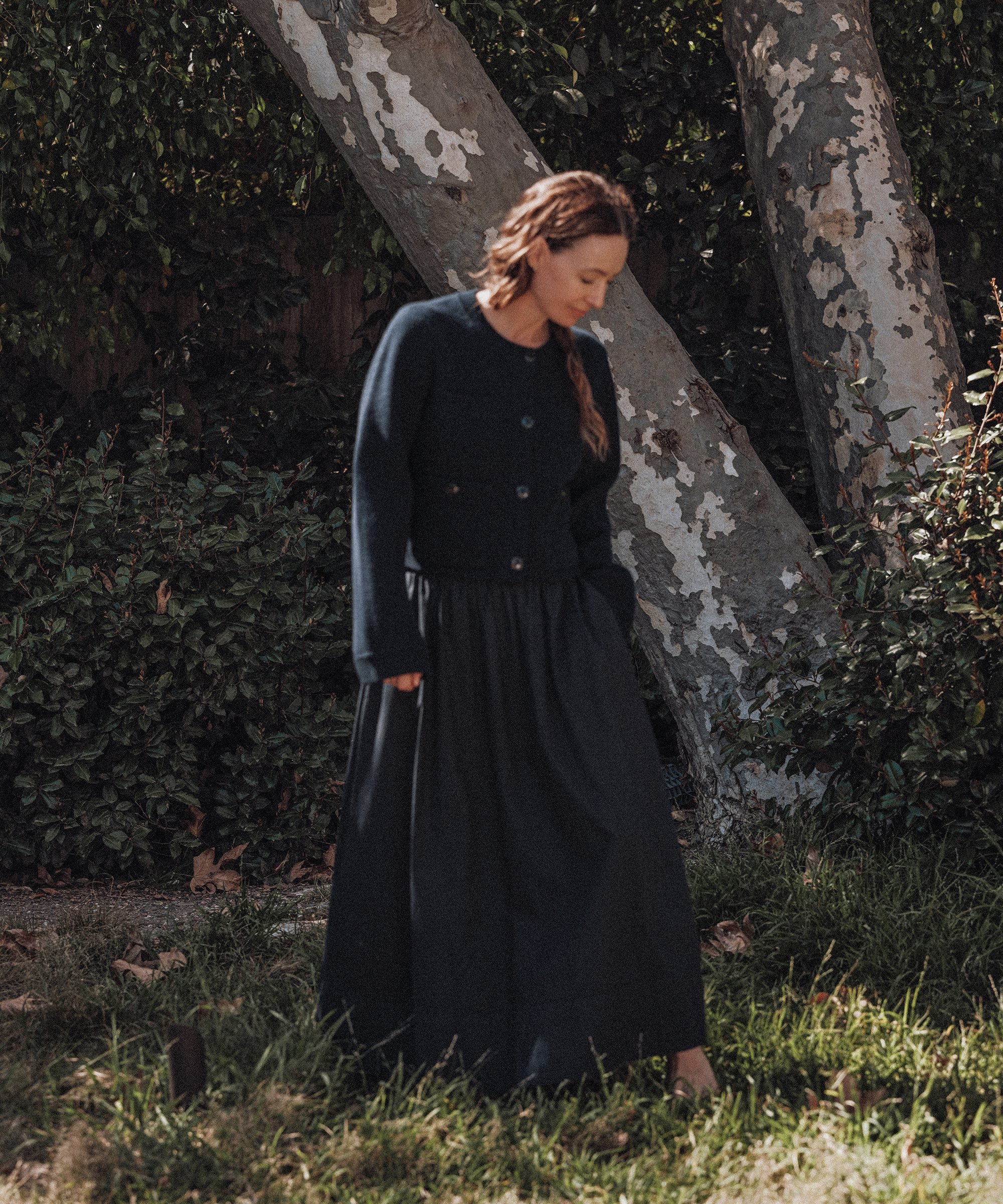 jenni wearing a navy structured cardigan and navy skirt outside next to a tree