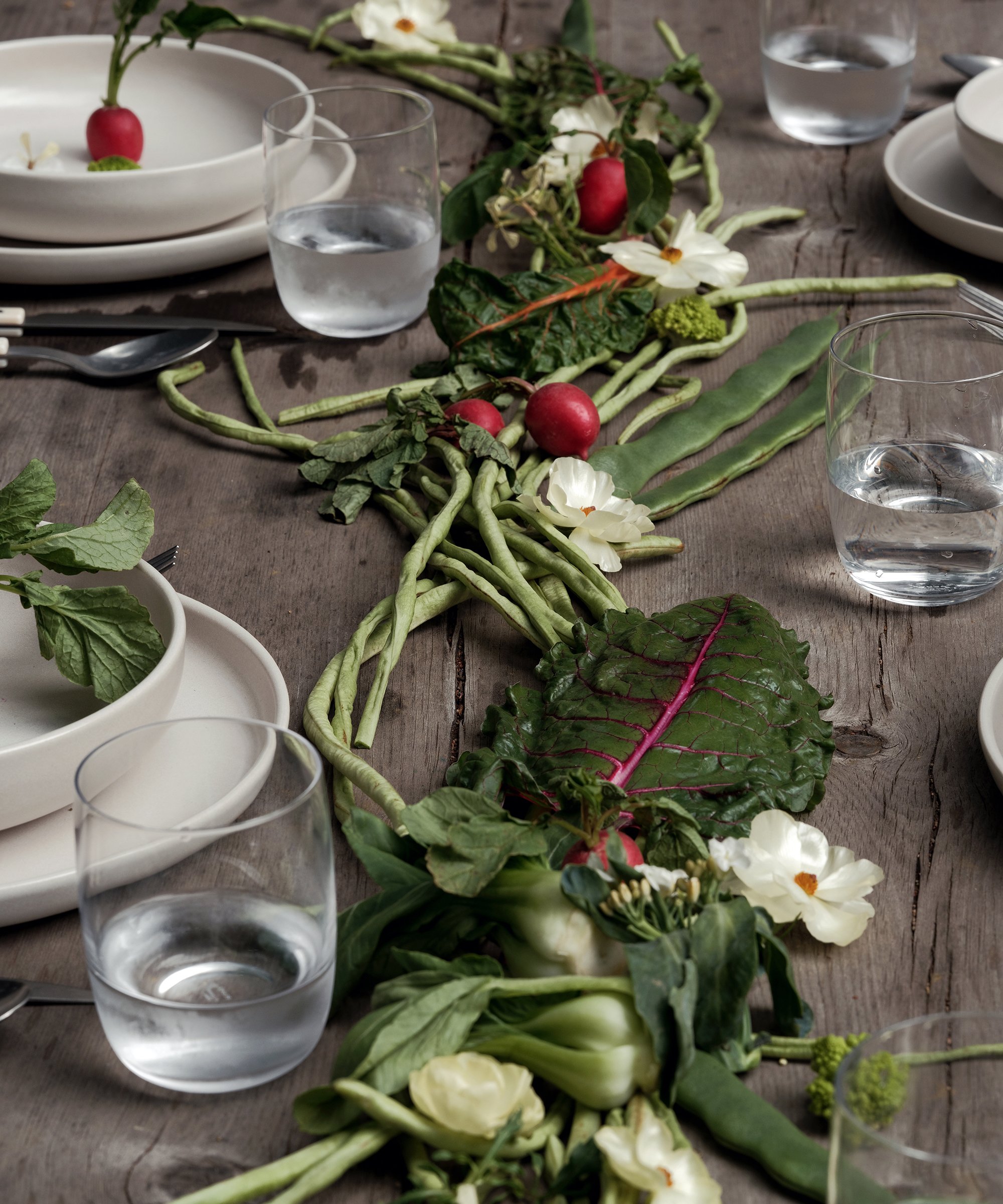 a wooden dining table with green beans and veggies on the table