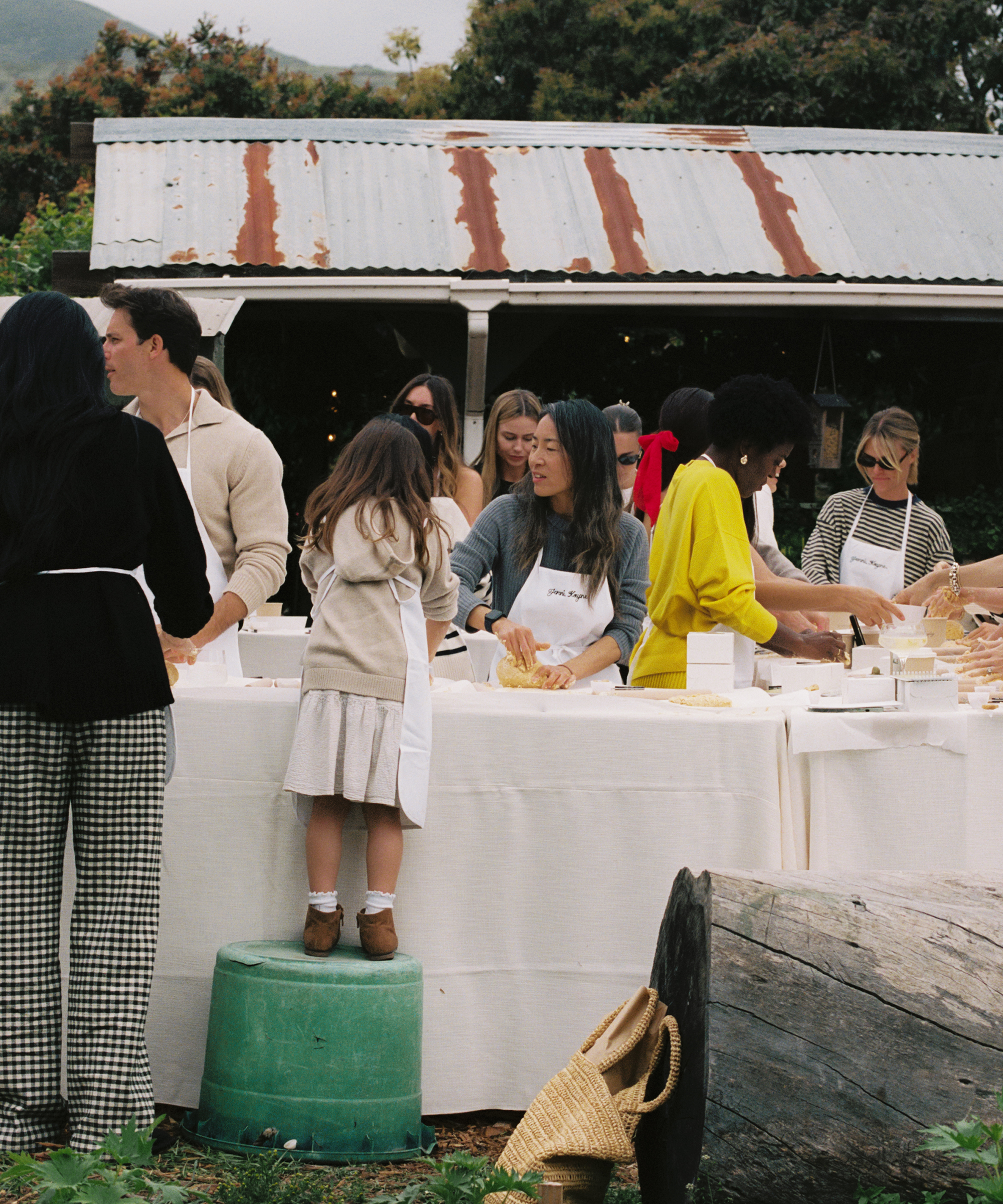 a cooking class outdoor with people at cooking tables with white linens