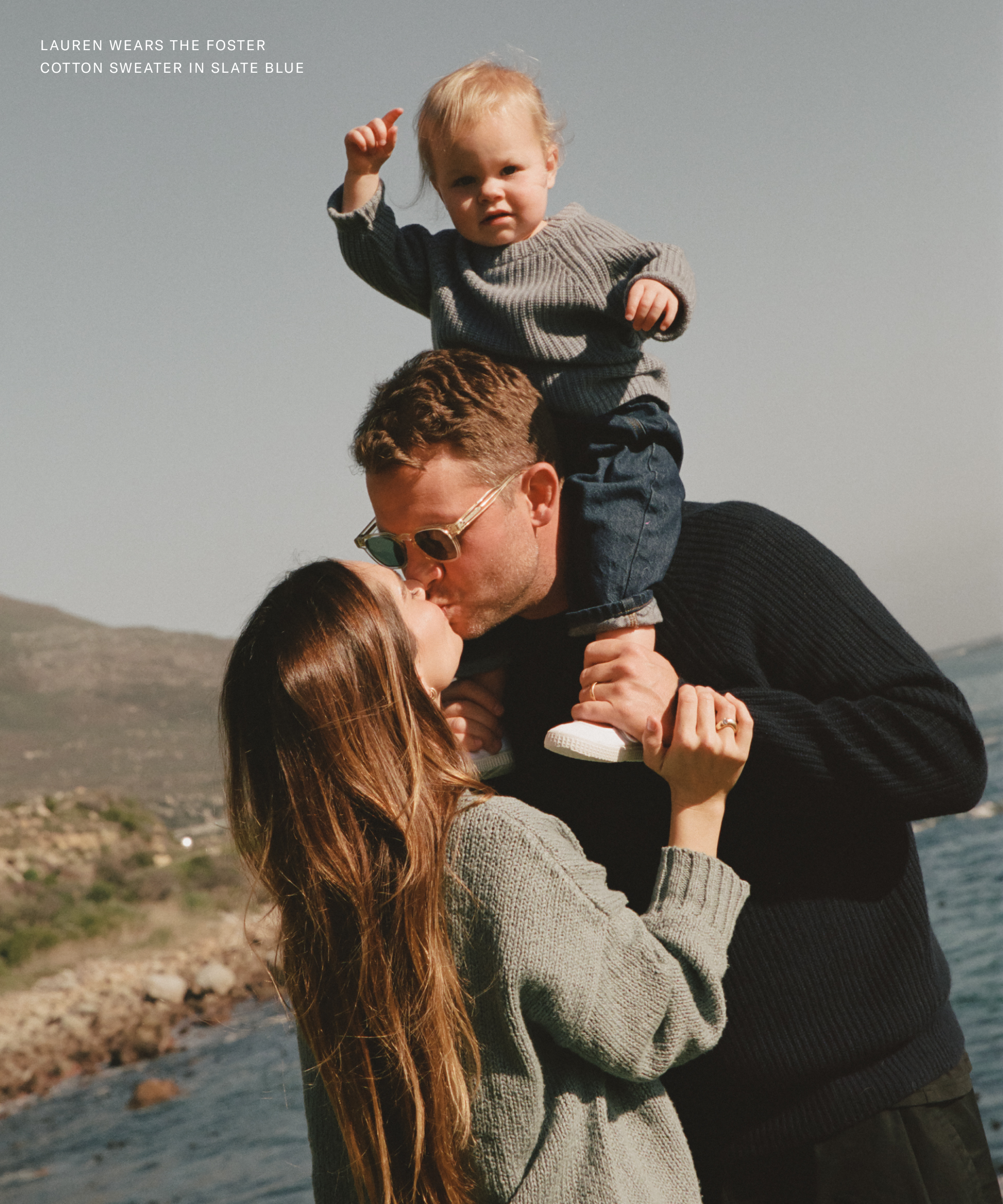 a family portrait wearing blue cashmere sweaters outside next to a body of water