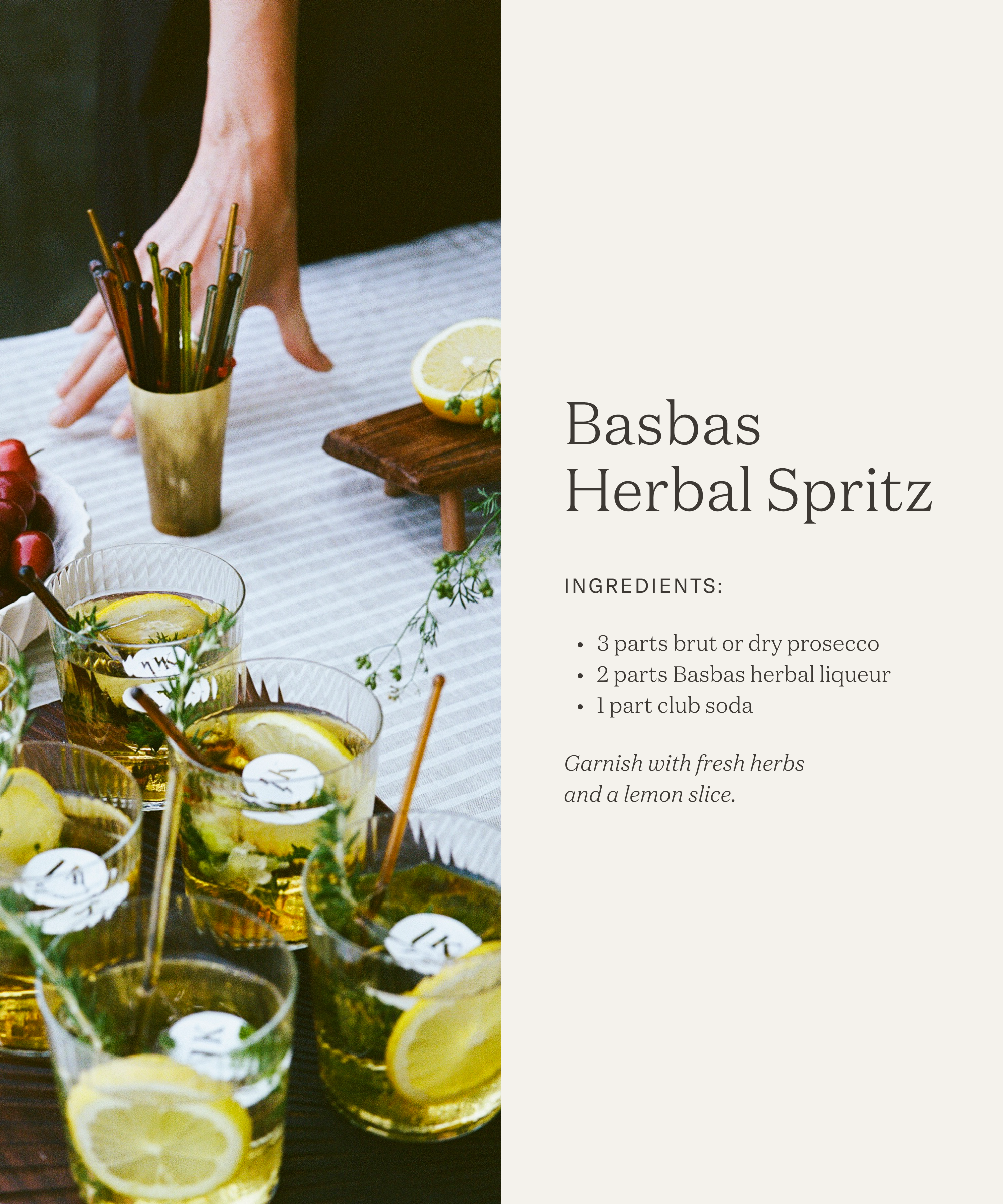 A hand reaches for a tall glass with gold straws beside four glasses of Basbas Herbal Spritz, garnished with lemon slices and herbs, styled by Leslie Kirchhoff, on a striped tablecloth with rosemary and drink recipe text on the side.