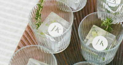a tray of glasses with custom jk logo square ice cubes and garnish