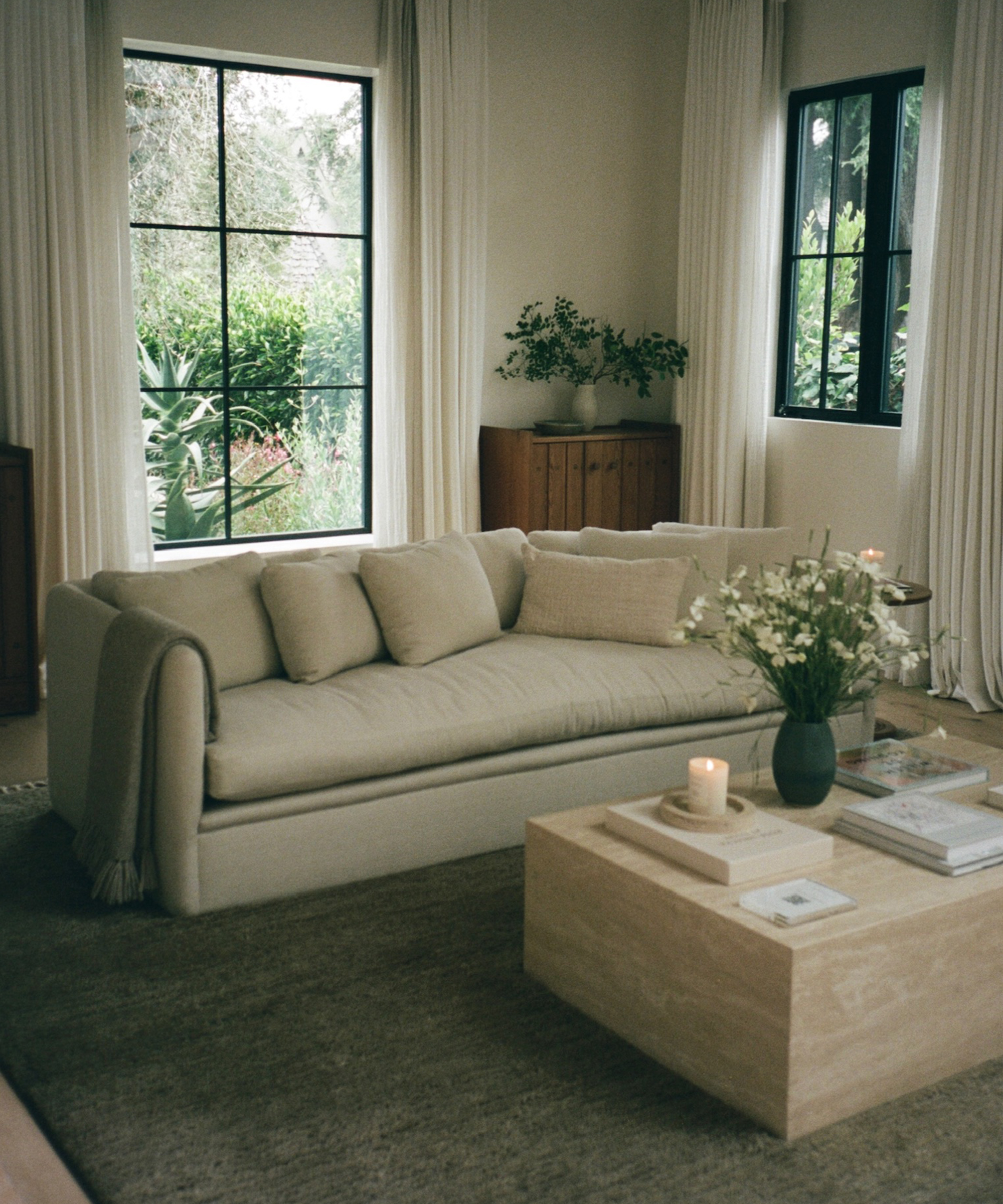 a living room with a dume sofa and travertine coffee table