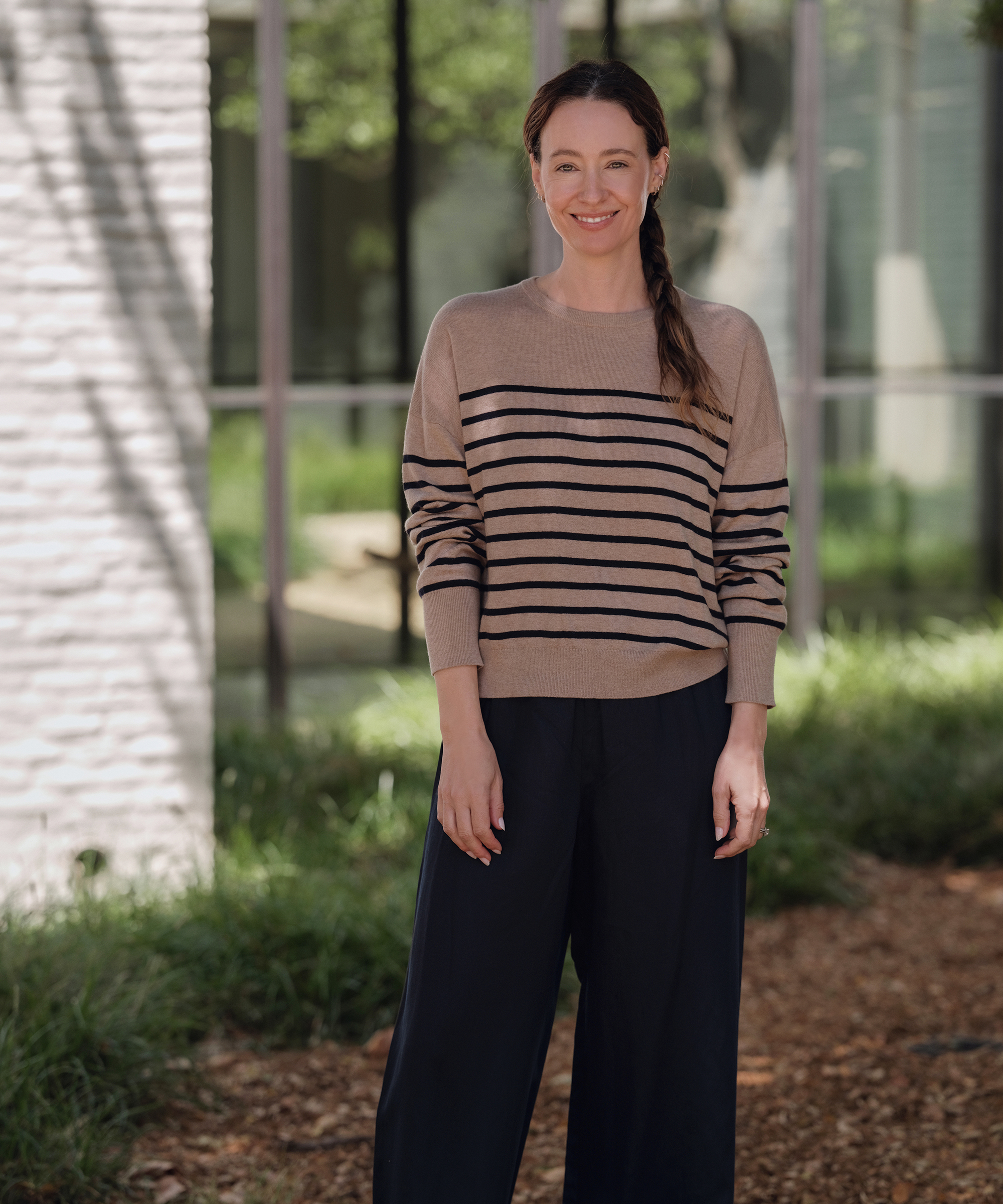 jenni standing outside wearing navy pants and a taupe and navy striped cashmere sweater