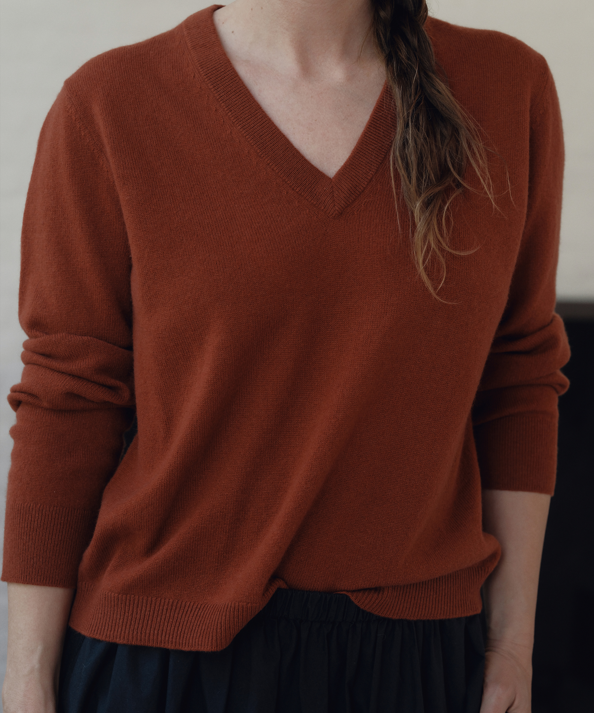 a detail shot of a cashmere vneck in a rust color