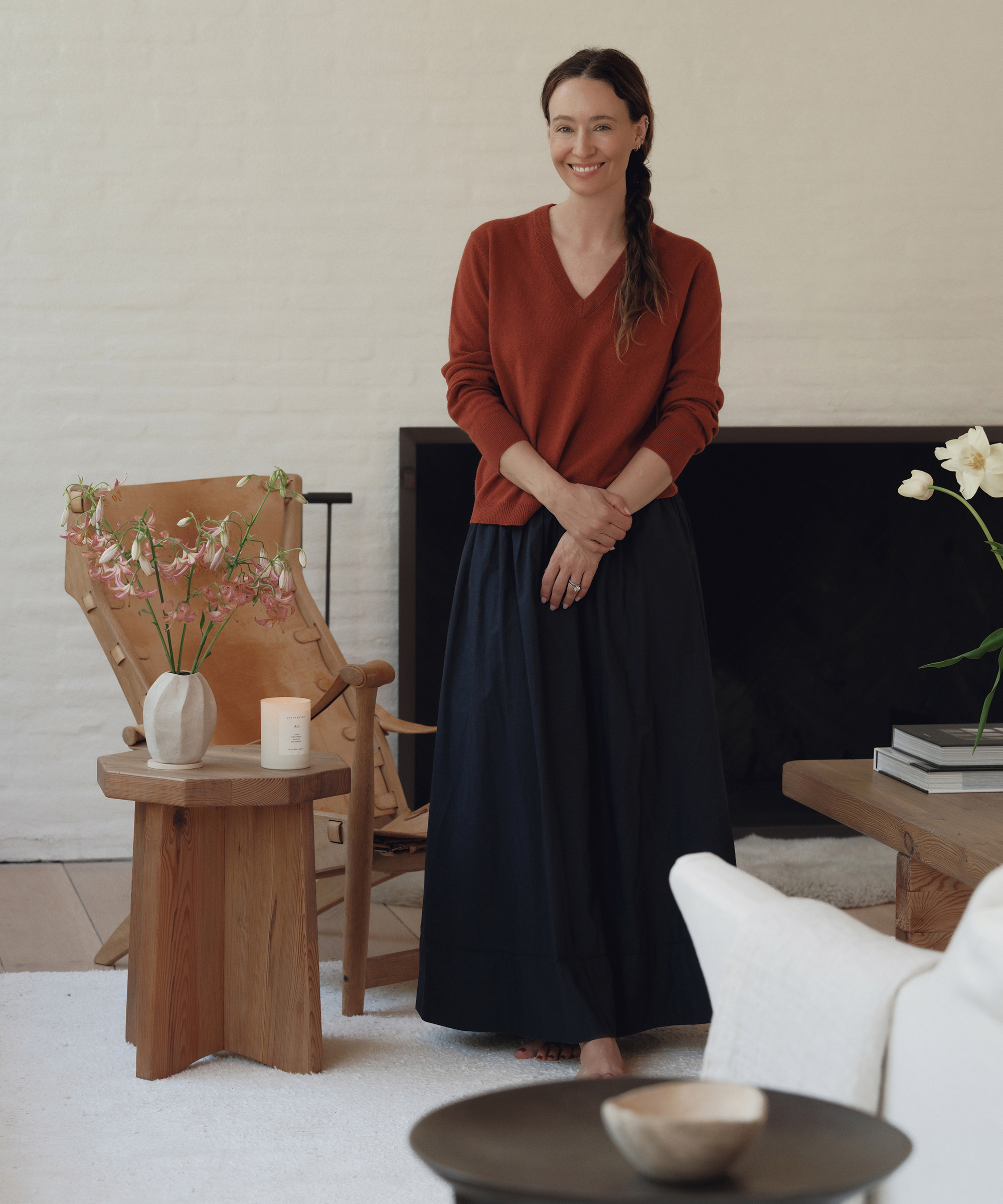 jenni wearing a cashmere vneck in rust and a navy long maxi skirt standing in her living room