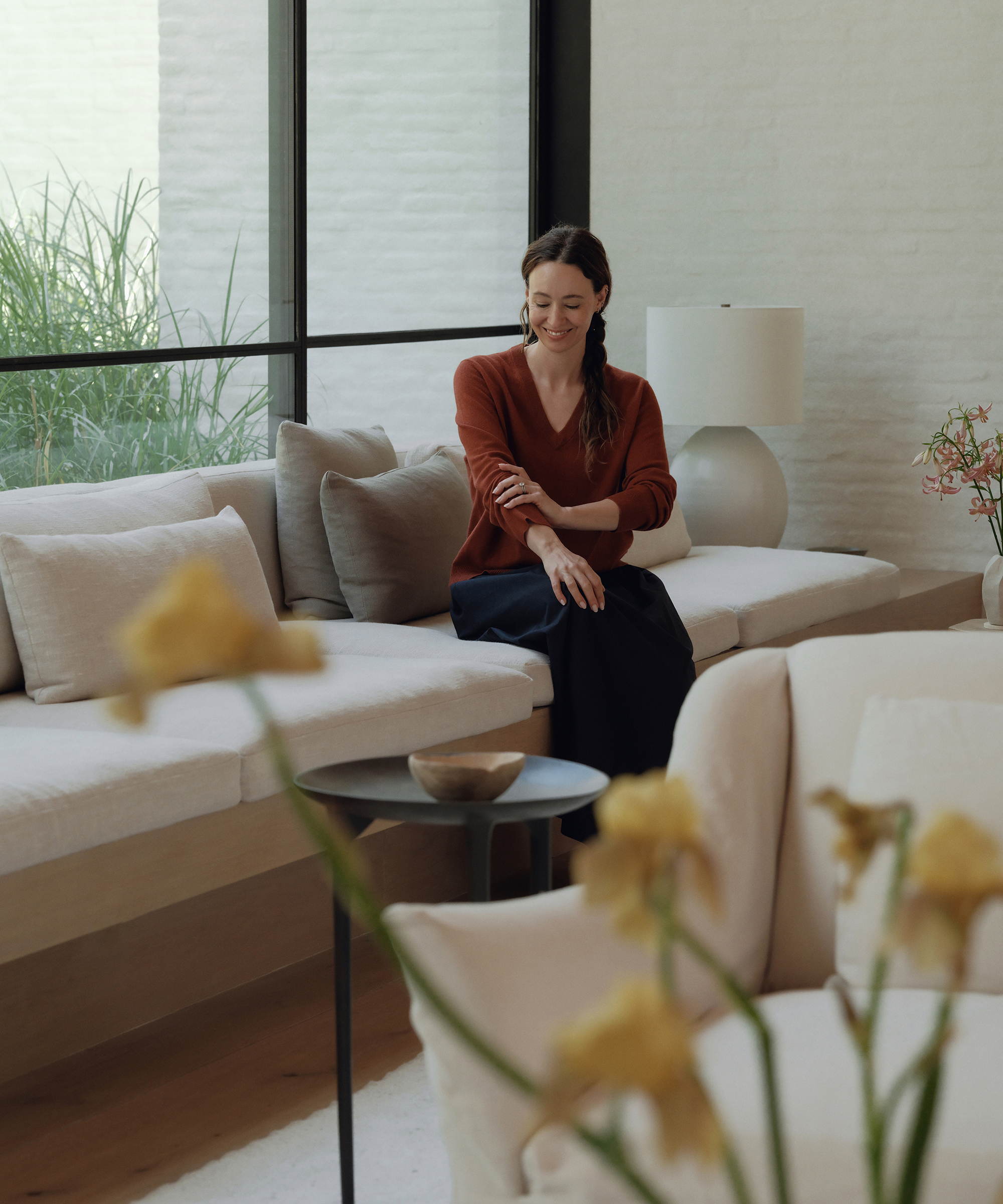 jenni sitting on a custom couch wearing a rust vneck